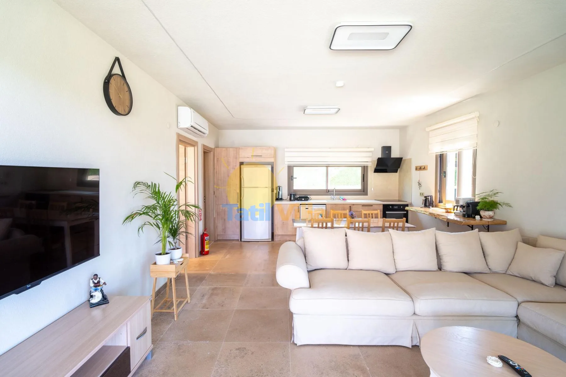 Una sala luminosa con una amplia zona de asientos y una cocina abierta.
