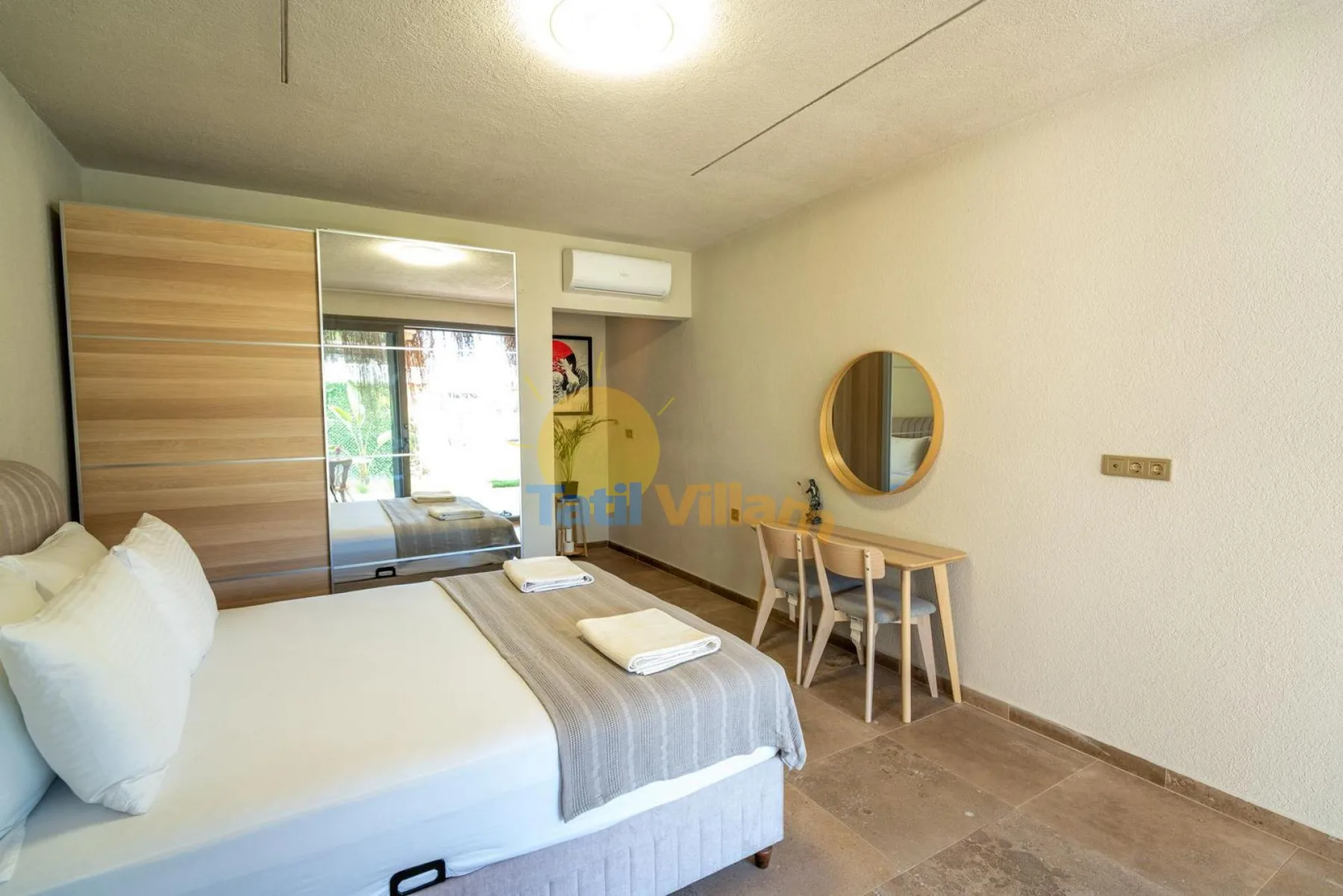 Dormitorio con cama, armario con espejo y una mesa pequeña.