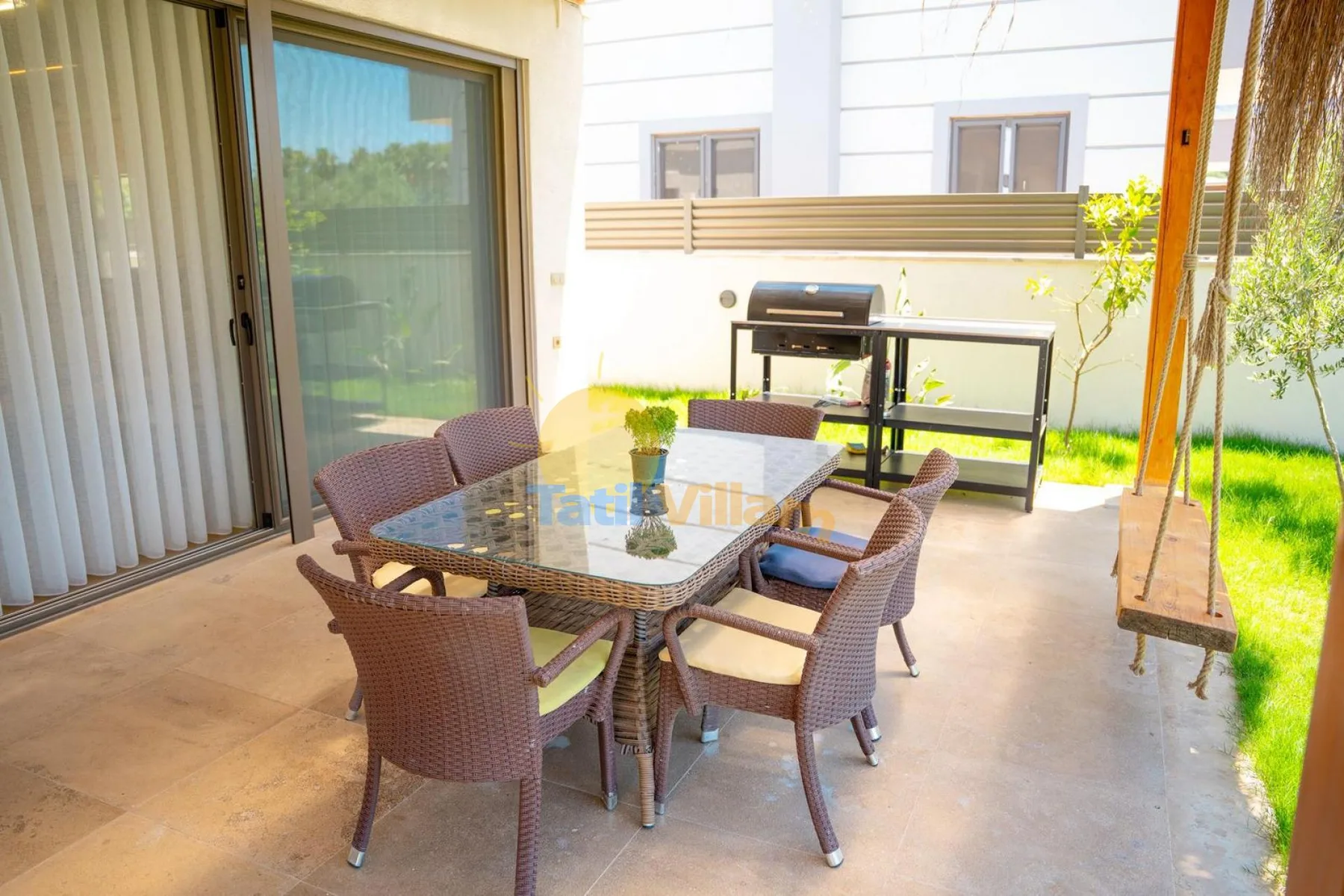 Un patio cubierto tiene una mesa de comedor con asientos y una parrilla.