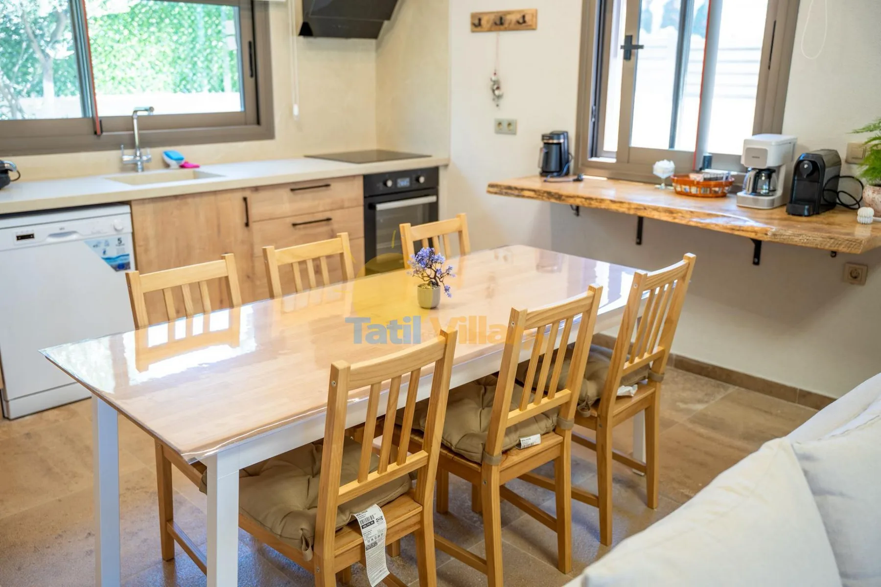 Una cocina y comedor con asientos de madera y una encimera bajo las ventanas.