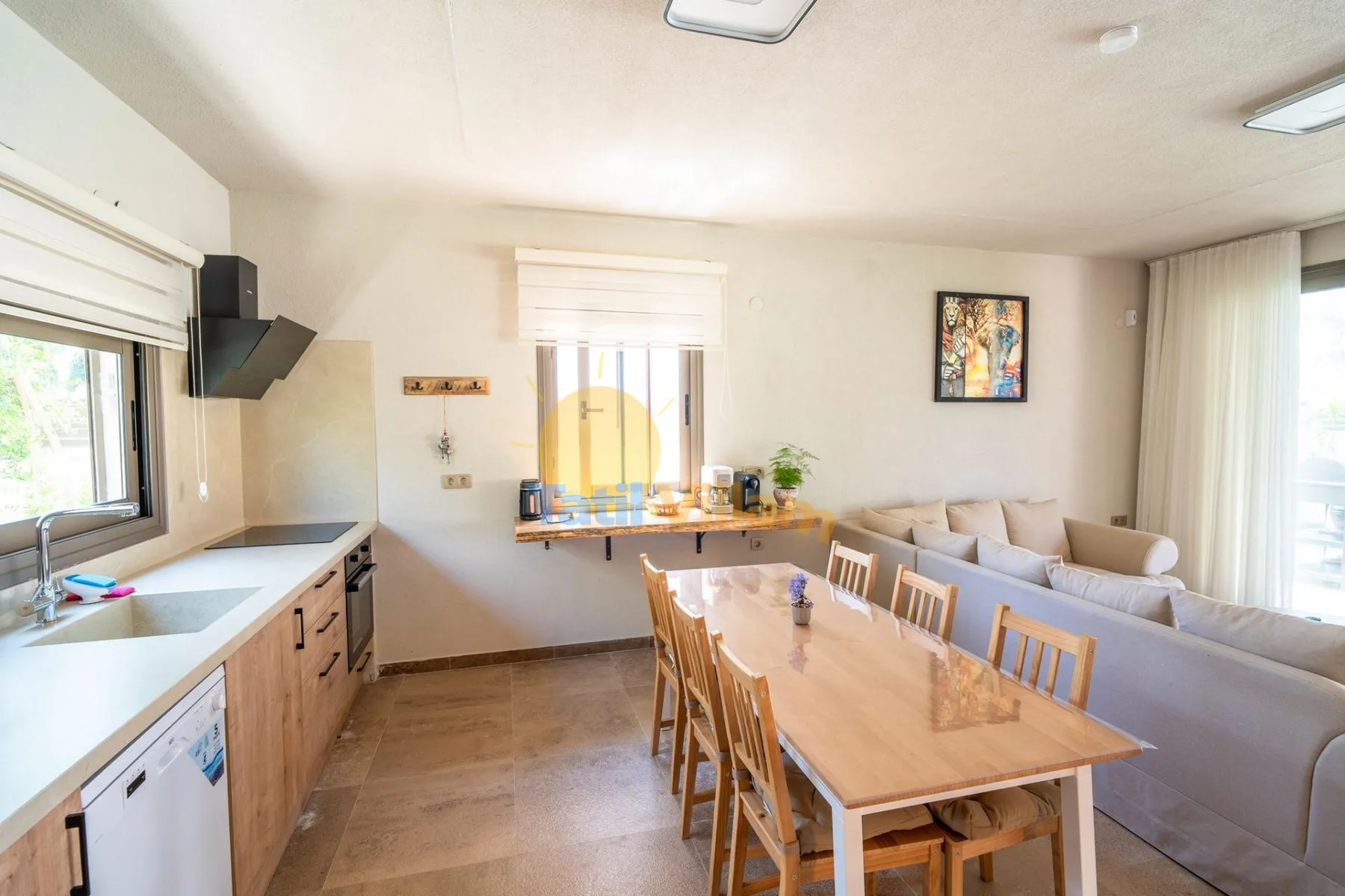 Un comedor y sala de estar de planta abierta, con una mesa larga junto a la encimera de la cocina.