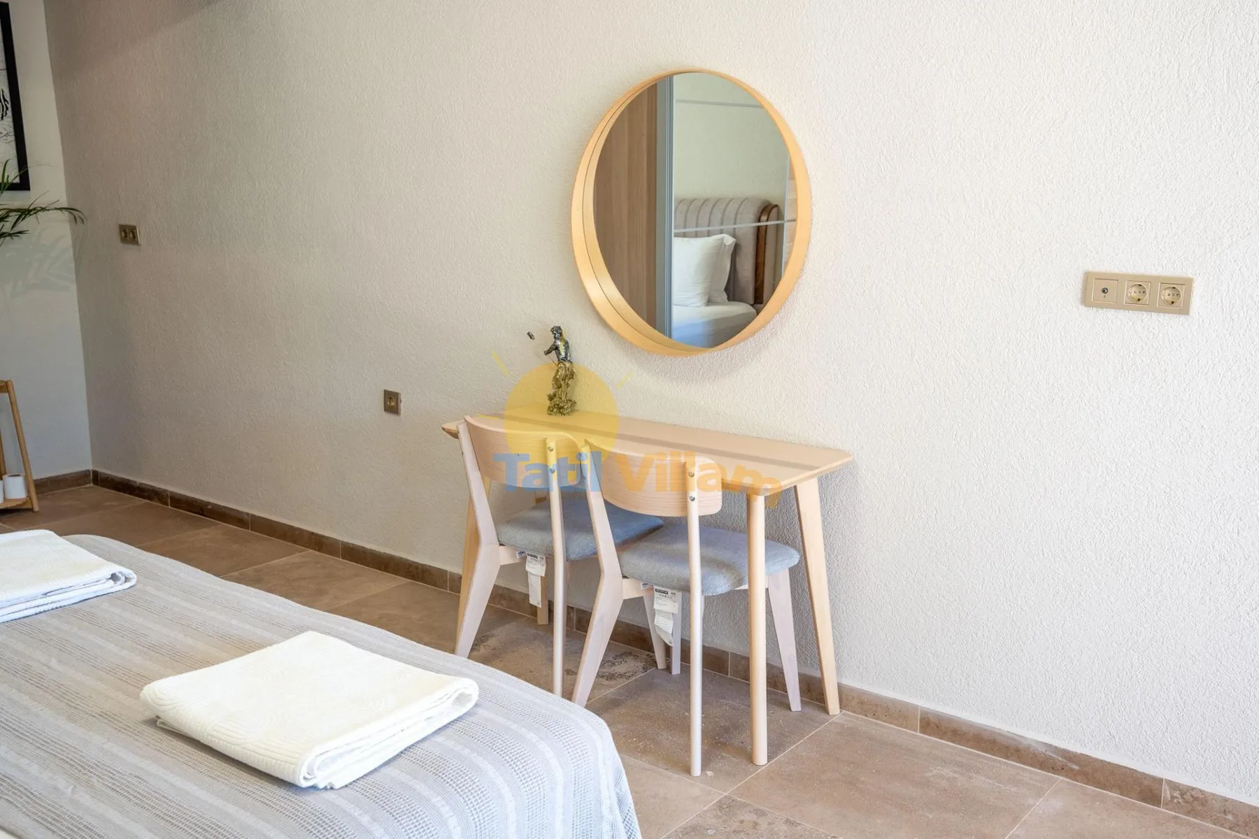Un dormitorio con un escritorio pequeño y un espejo redondo en la pared junto a la cama.