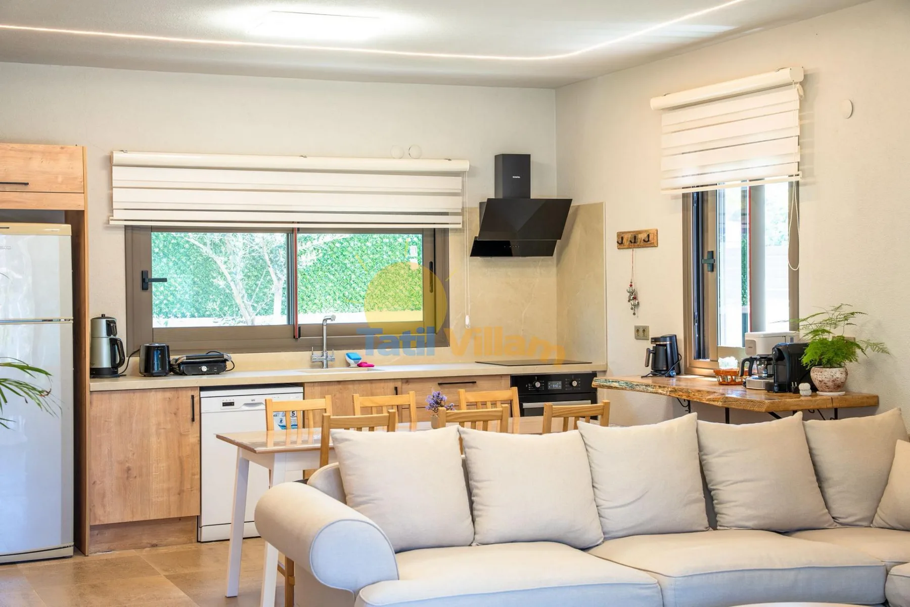 Una cocina y sala de estar luminosa con un sofá claro en primer plano.