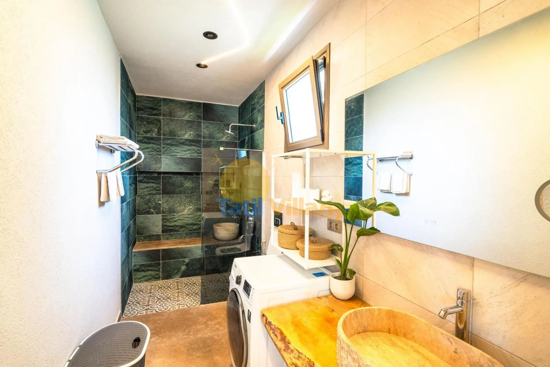 Un baño luminoso con ducha, lavabo y lavadora.
