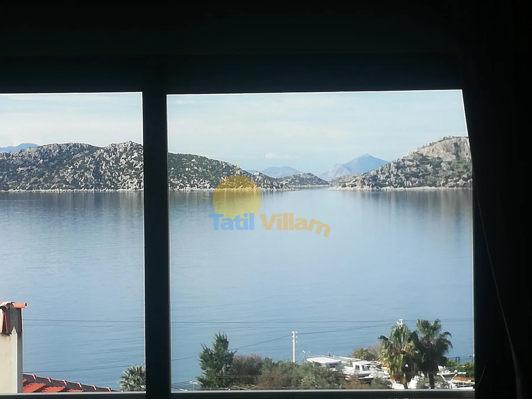 A broad lake view is framed by dark window panes and distant hills.