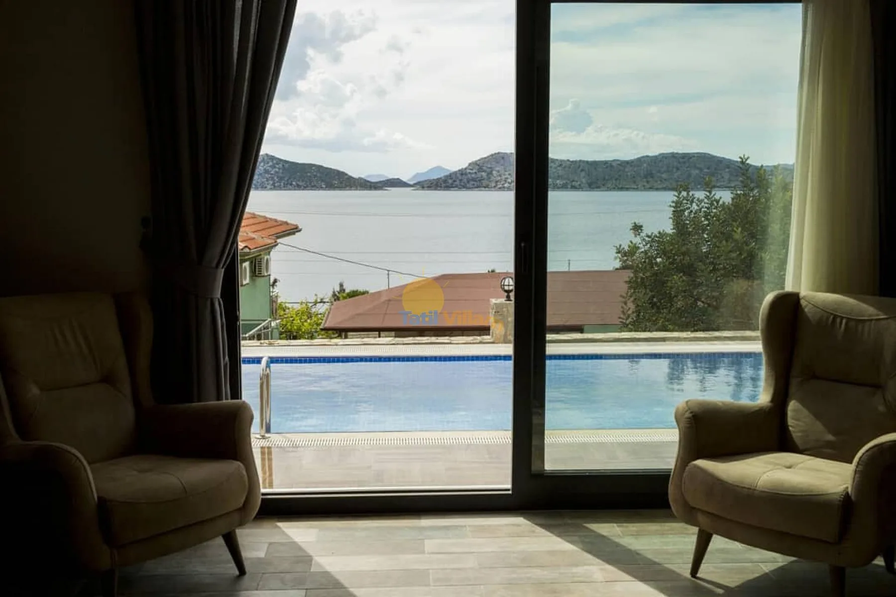 A sitting area overlooks a swimming pool and the water beyond.