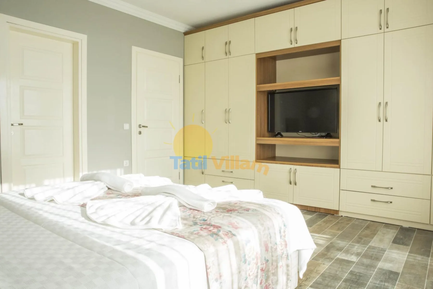 A bedroom with a bed and built-in cabinets surrounding a television.