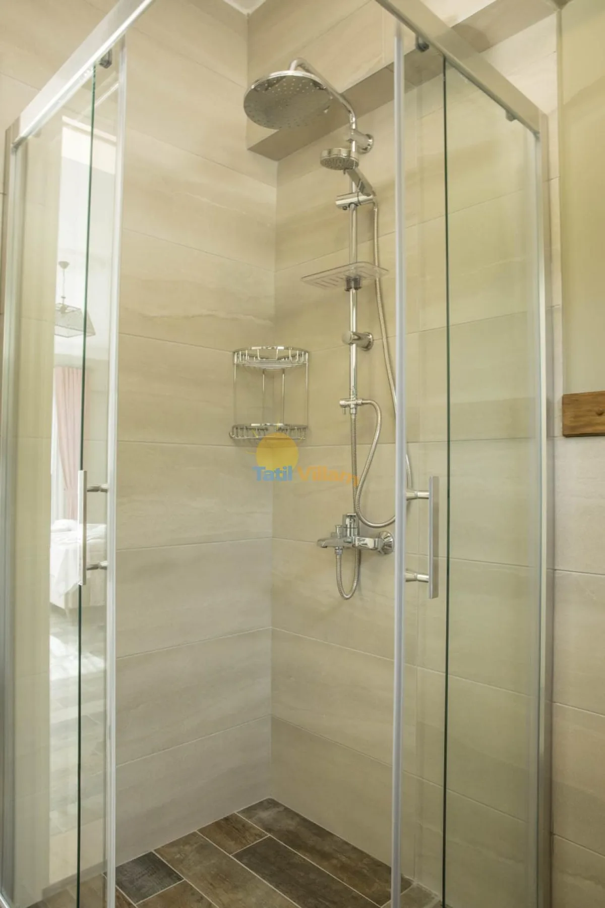 A tiled shower with glass panels and a wall-mounted shower fixture.