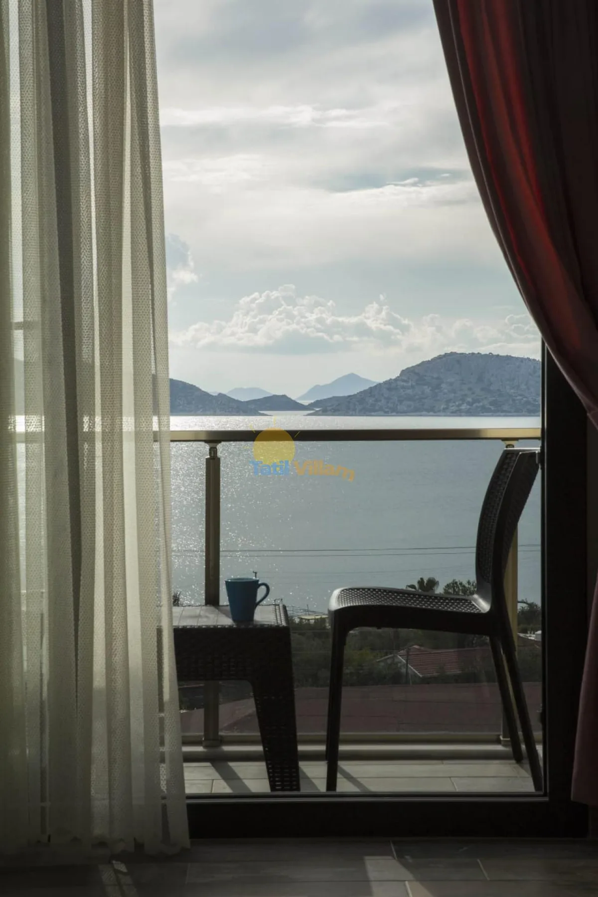 A balcony seating area overlooks the water and distant hills.