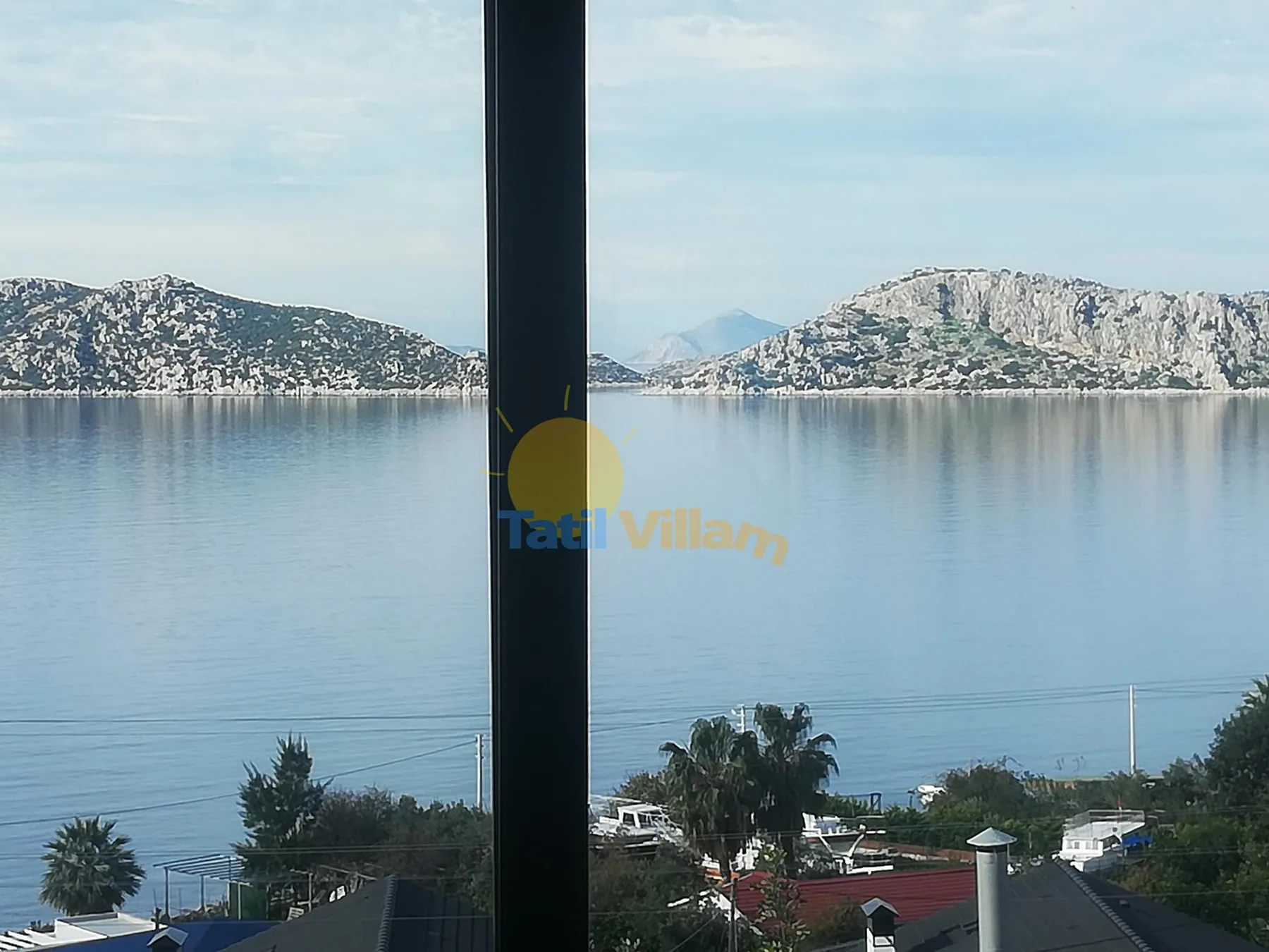 A view of a calm bay and rocky hills through a window.