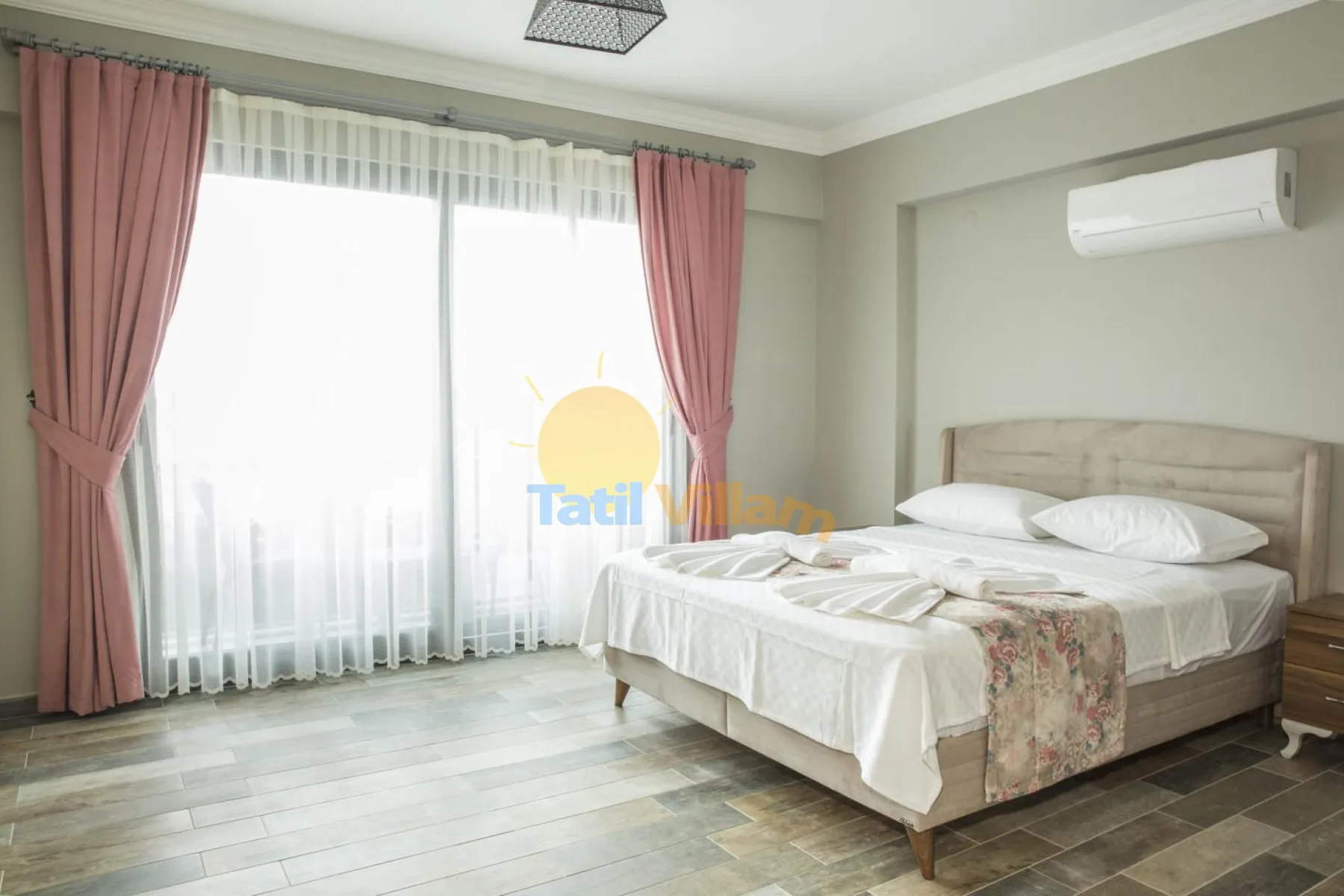 A bedroom with a bed beside a large curtained window.