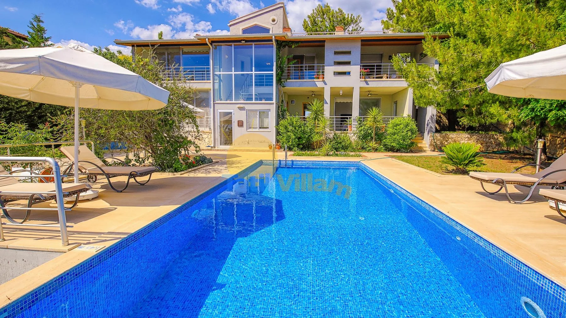 A swimming pool and sun loungers sit in front of a modern building.