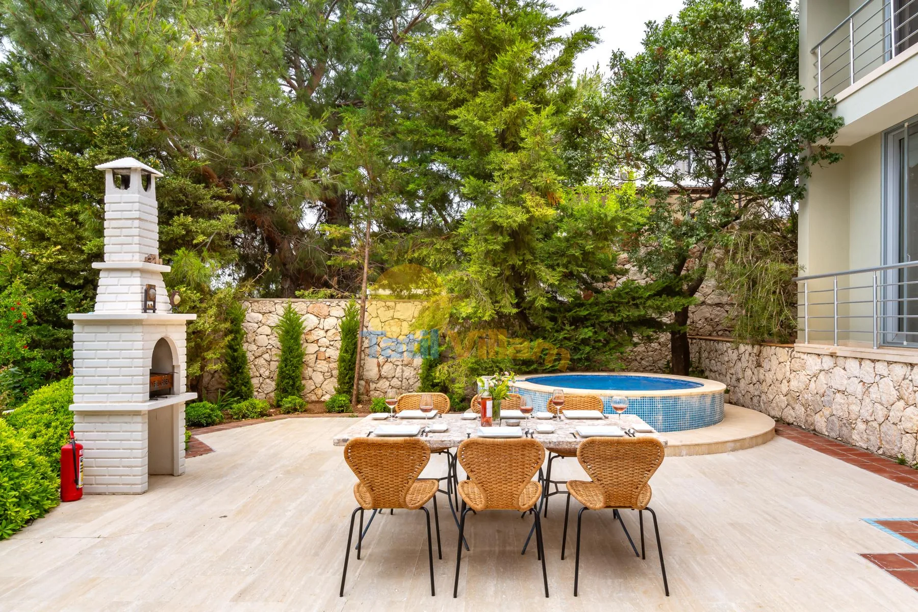 An outdoor patio with a dining table, a built-in barbecue, and a small pool.