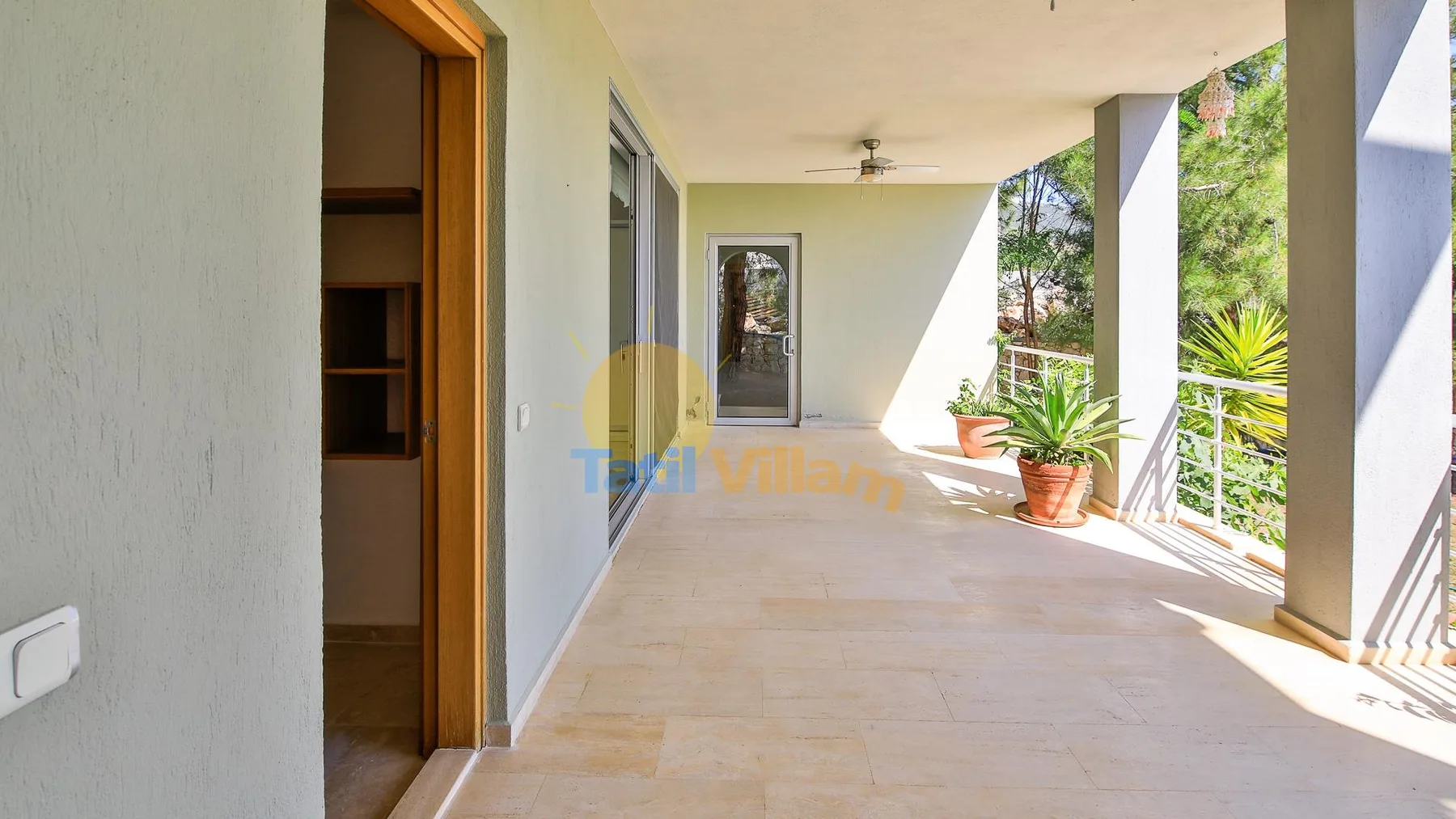 A covered outdoor terrace with tiled flooring, columns, and potted plants.