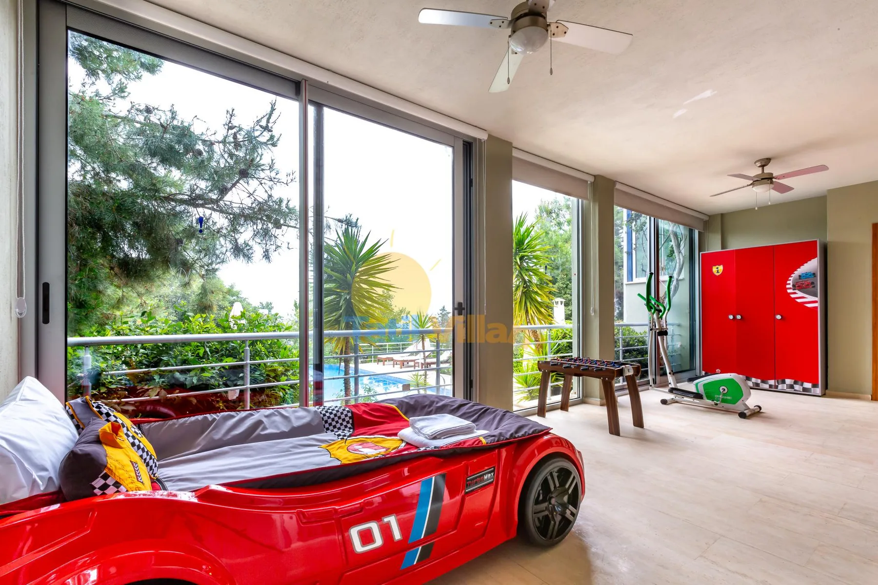 A bedroom with a red race-car-shaped bed beside large windows.