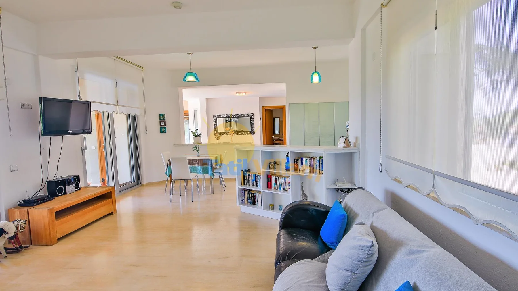 A bright living and dining area has seating, a television, and a dining table.
