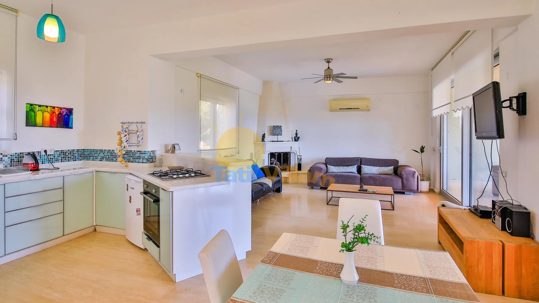 A bright open-plan living room and kitchen with a dining table and sofa.
