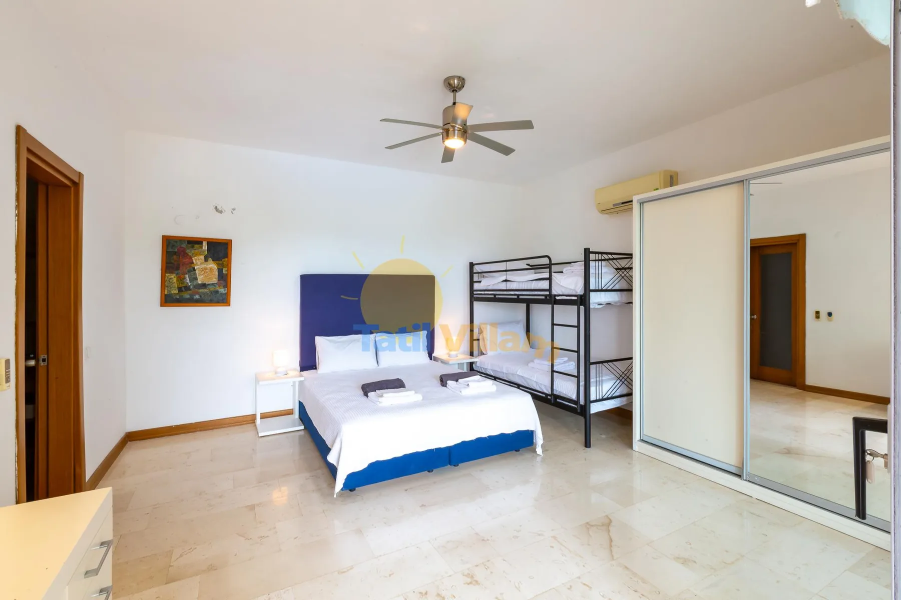 A bedroom with a double bed, bunk beds, and a mirrored wardrobe.