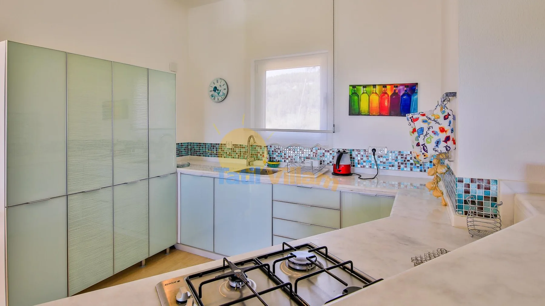 A bright kitchen with pale cabinetry, a tiled backsplash, and a gas cooktop.