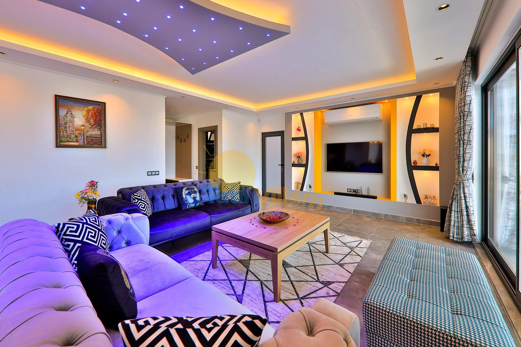 A modern living room with seating arranged around a coffee table and television.