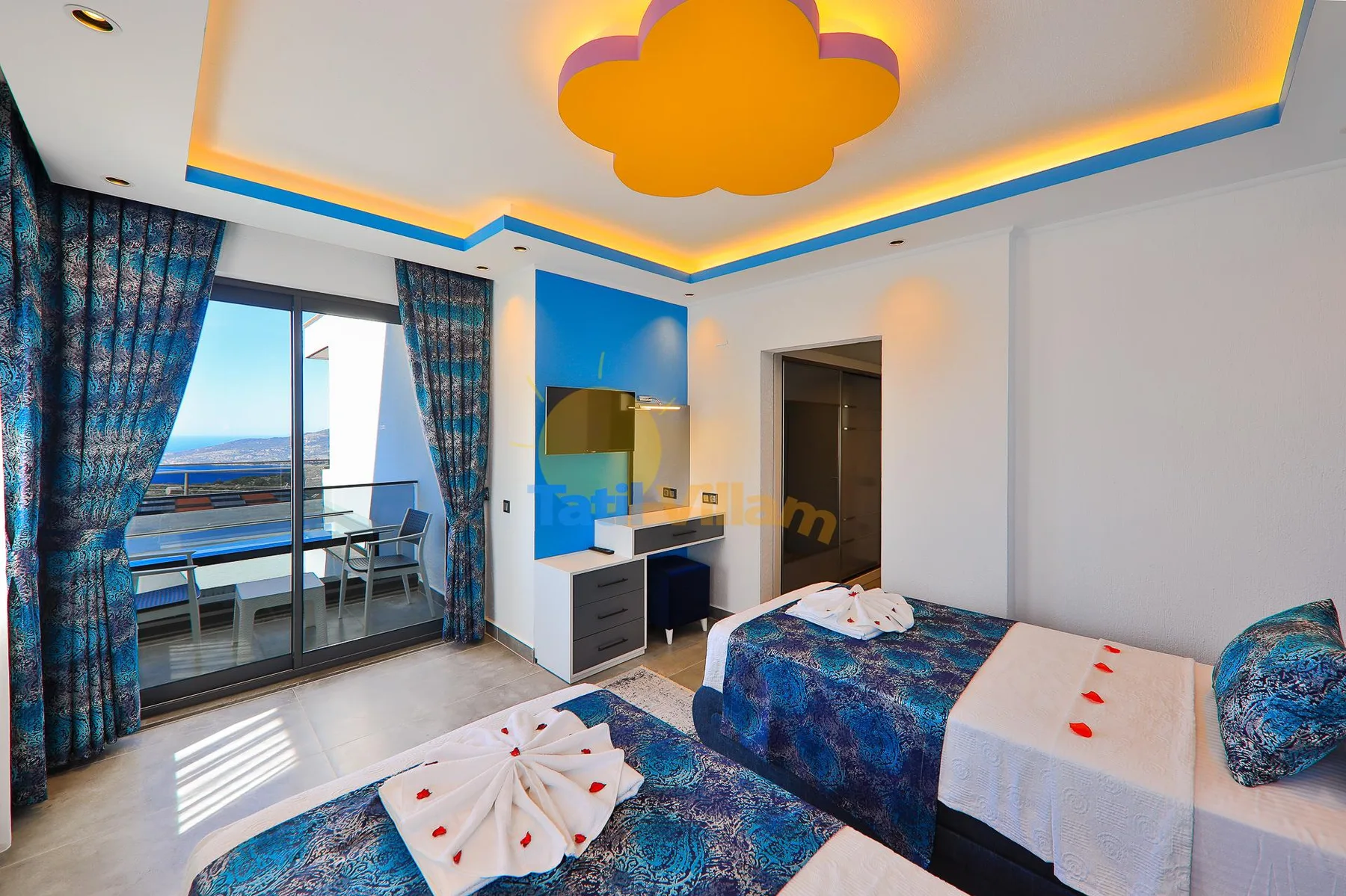 A bright bedroom with blue bedding and sliding glass doors opening onto a balcony.