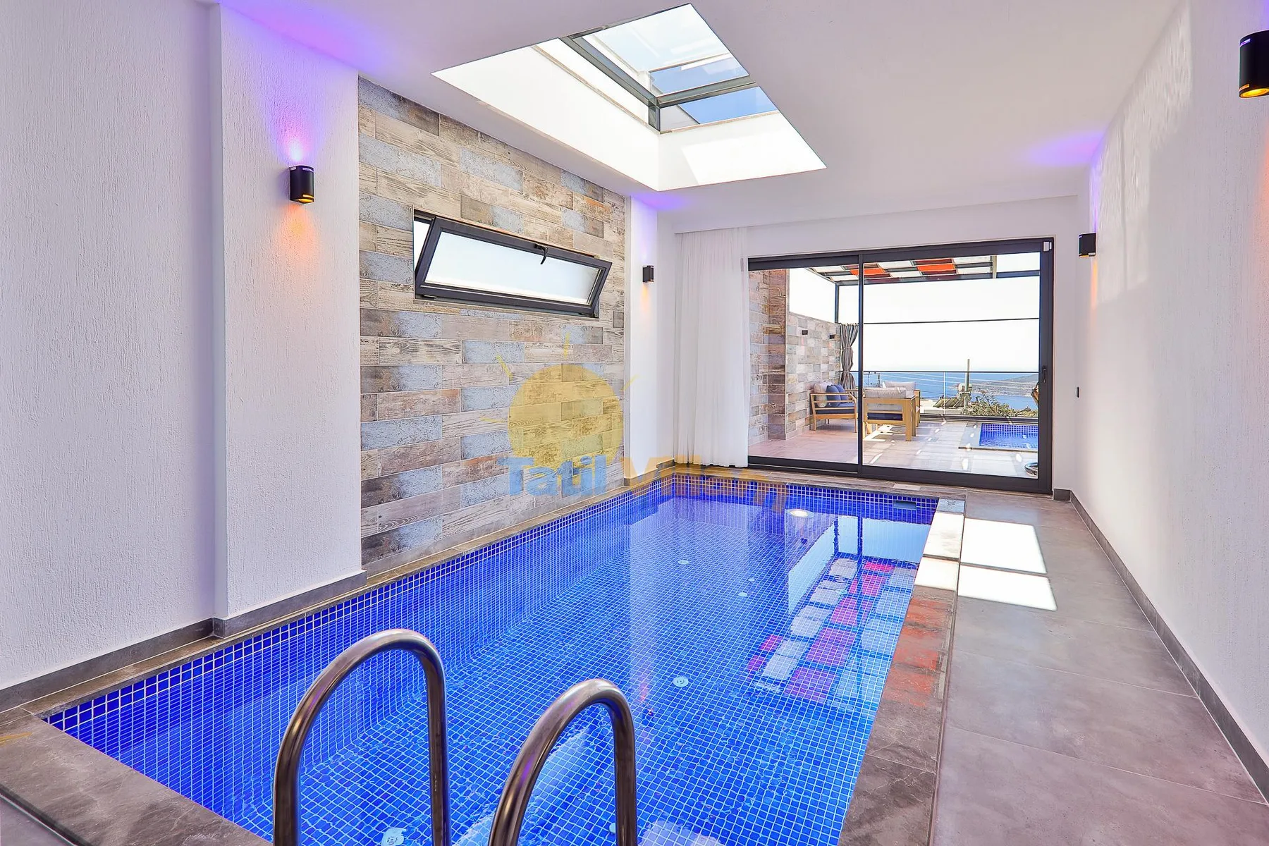 An indoor pool with blue tile flooring and a skylight overhead.