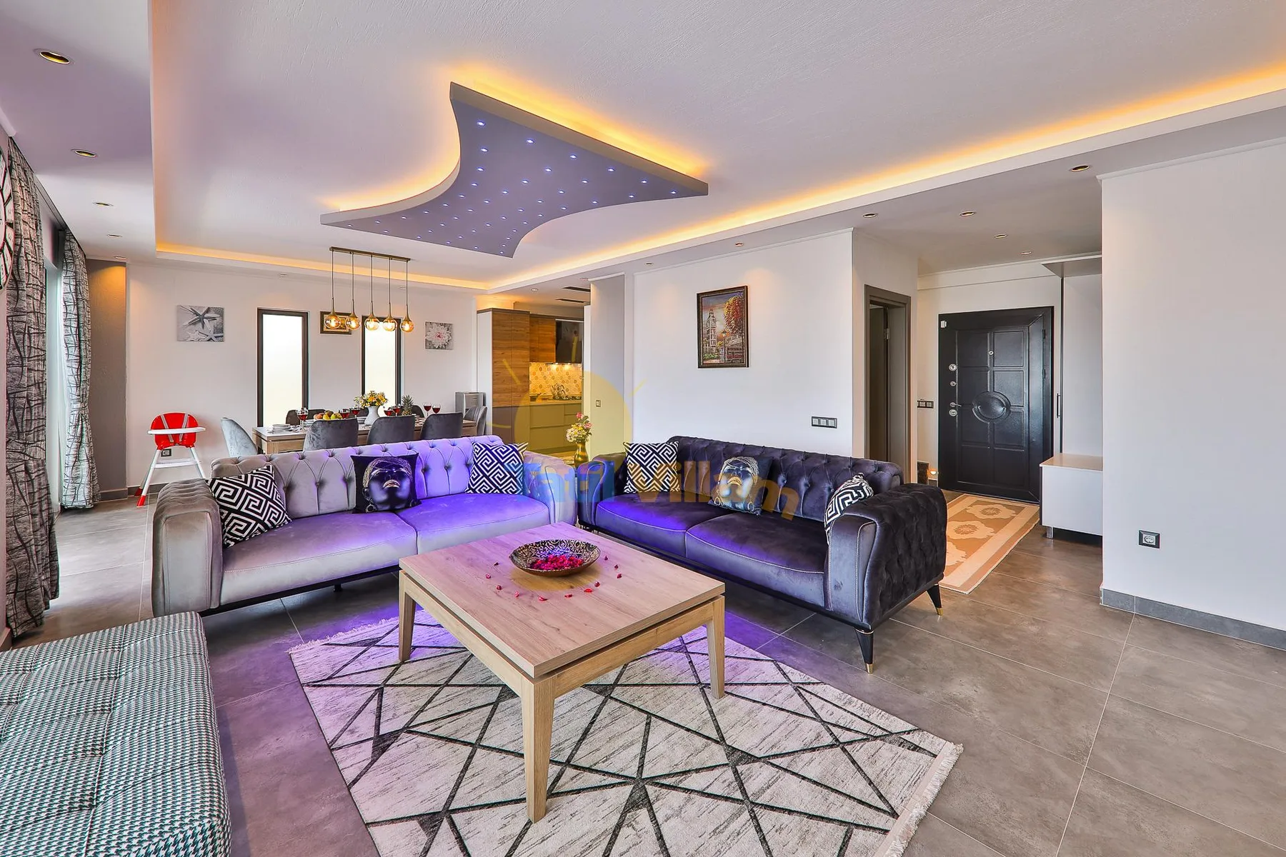 A modern living room with seating around a coffee table and a dining area beyond.