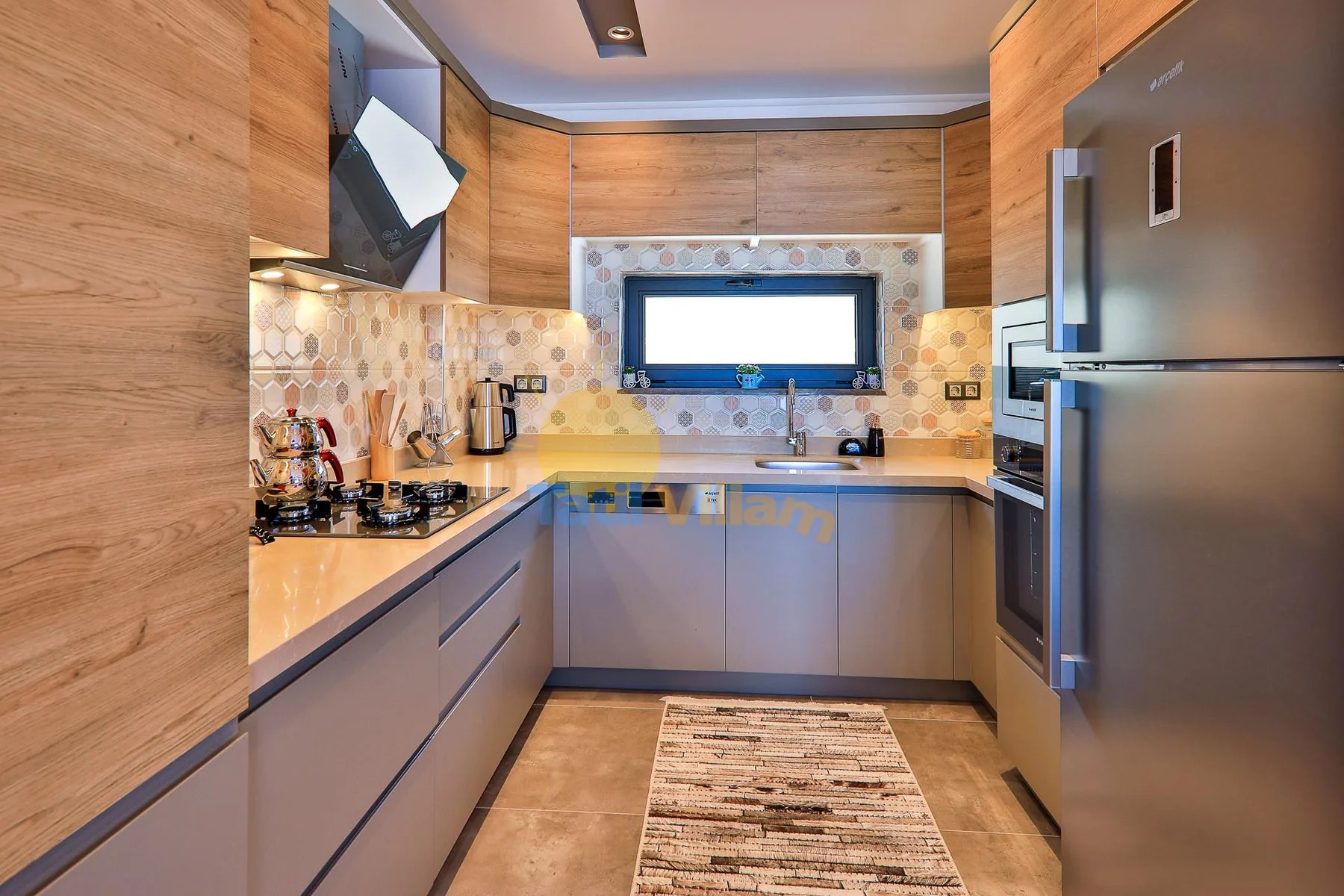 A compact kitchen with L-shaped counters, cabinets, and stainless steel appliances.