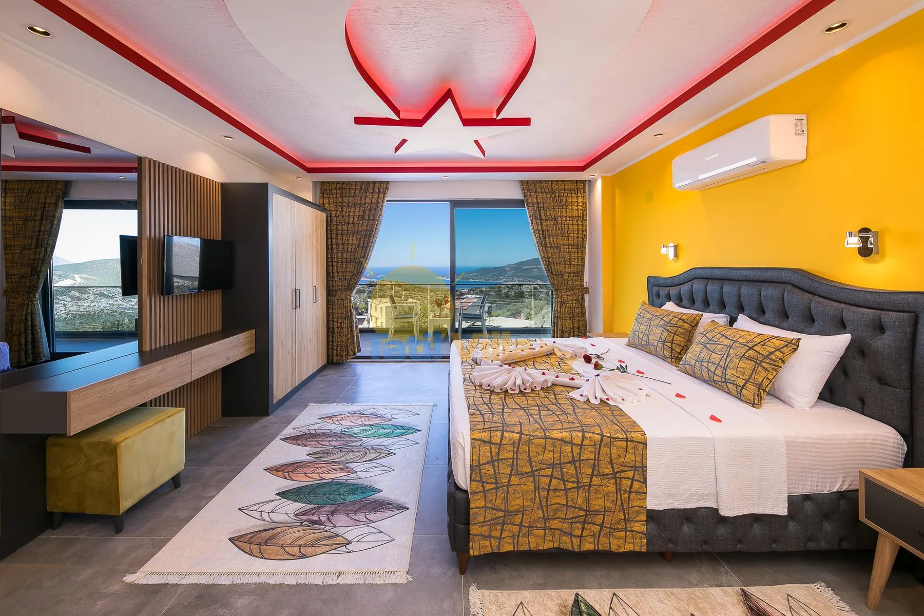 A bedroom with a large bed, bright yellow walls, and a window overlooking the sea.