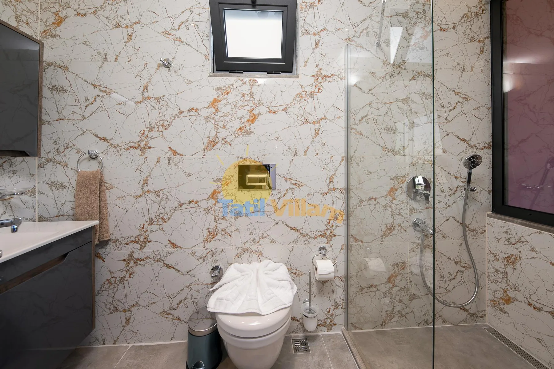 A bathroom with a toilet, sink, and glass shower enclosure.