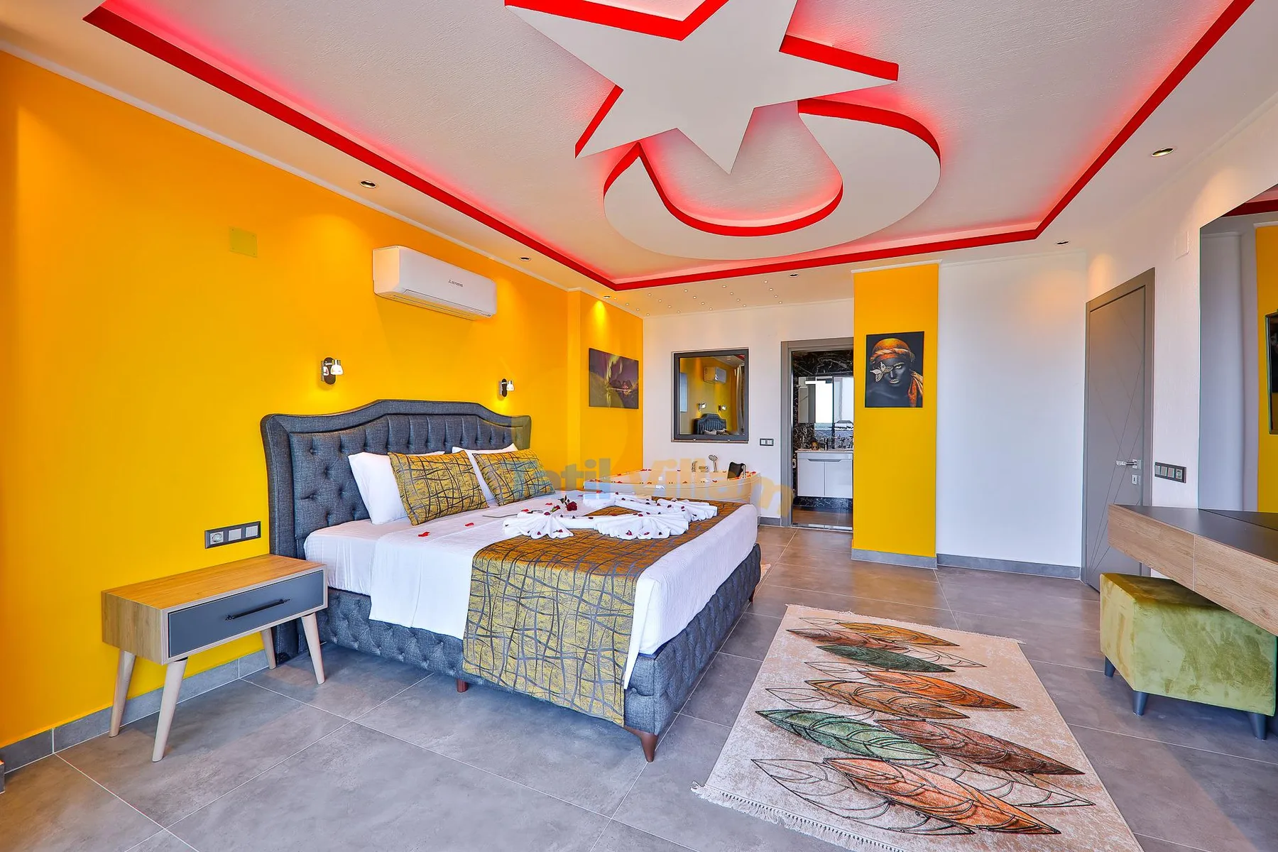 A bedroom with a large bed, yellow walls, and a patterned rug.