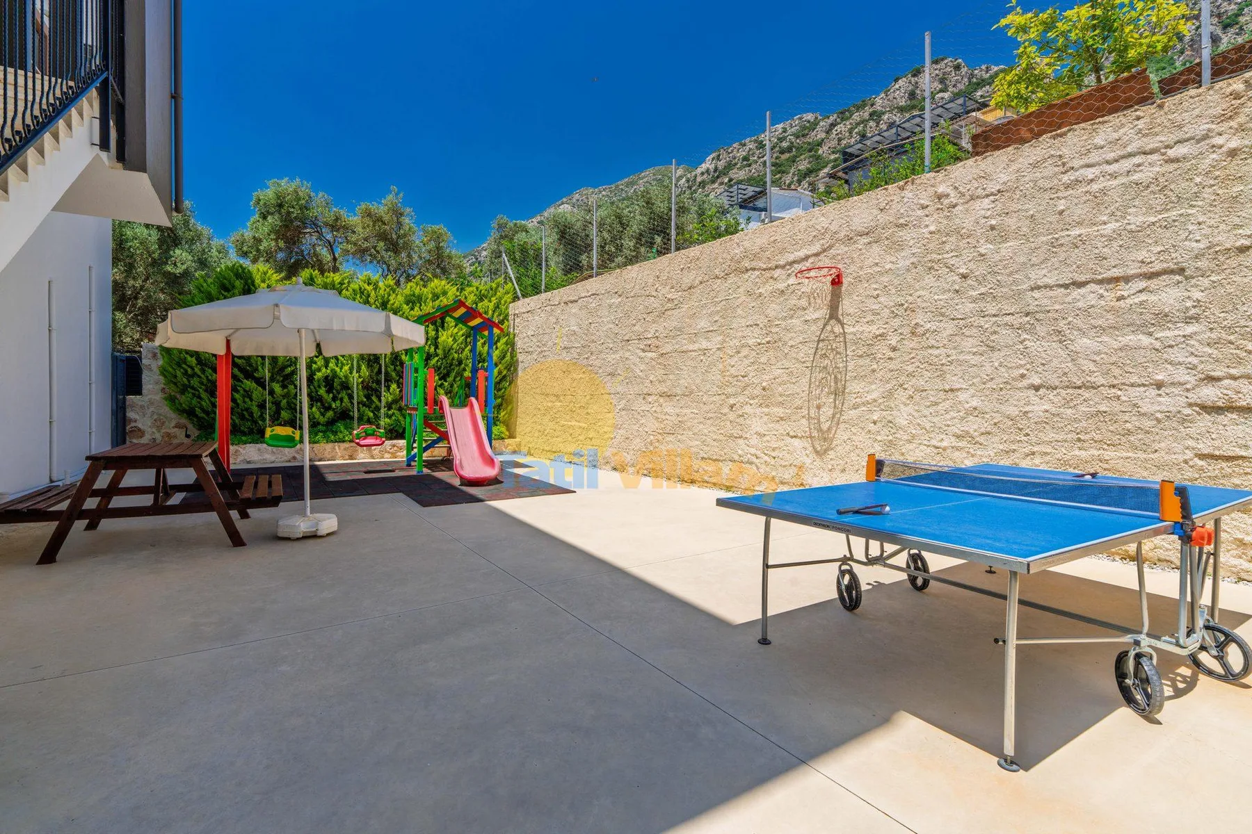 An outdoor recreation area with a table tennis table and a small slide.