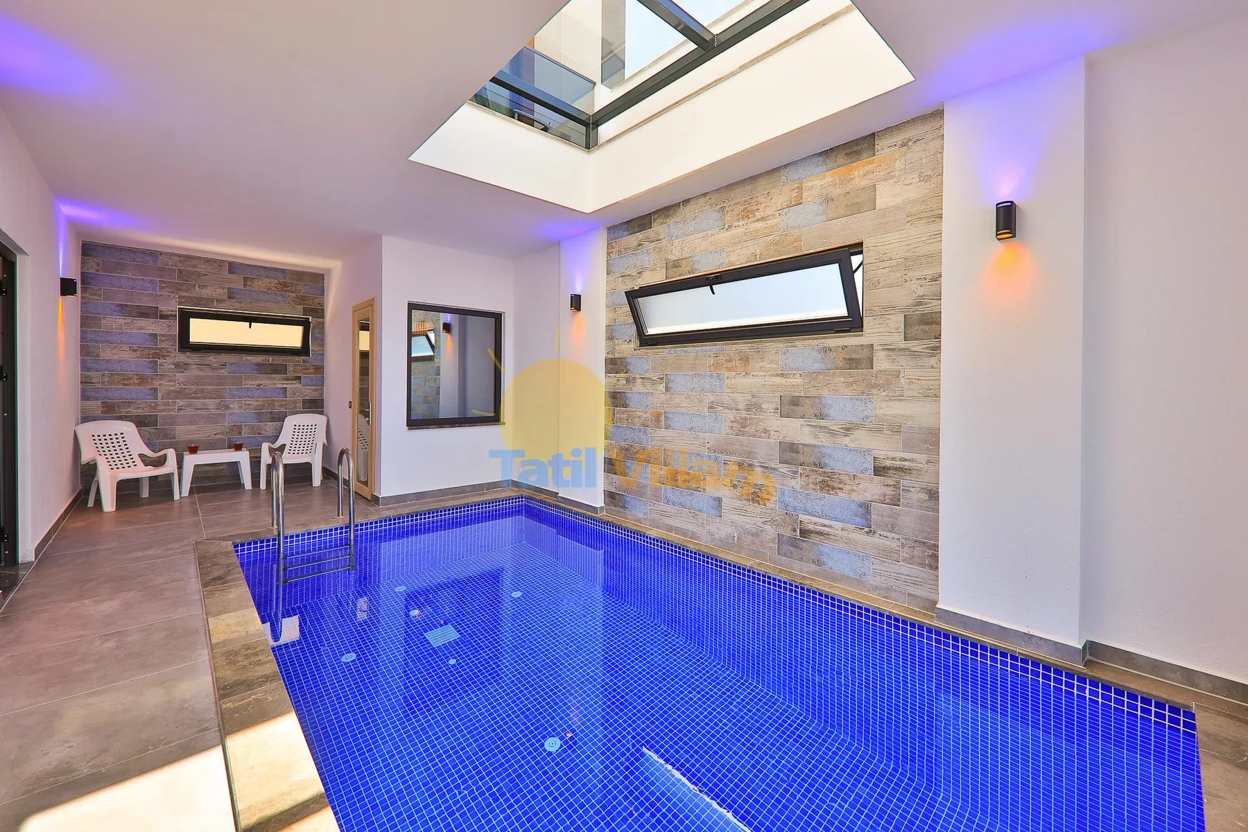 An indoor swimming pool with blue tile and a large skylight.