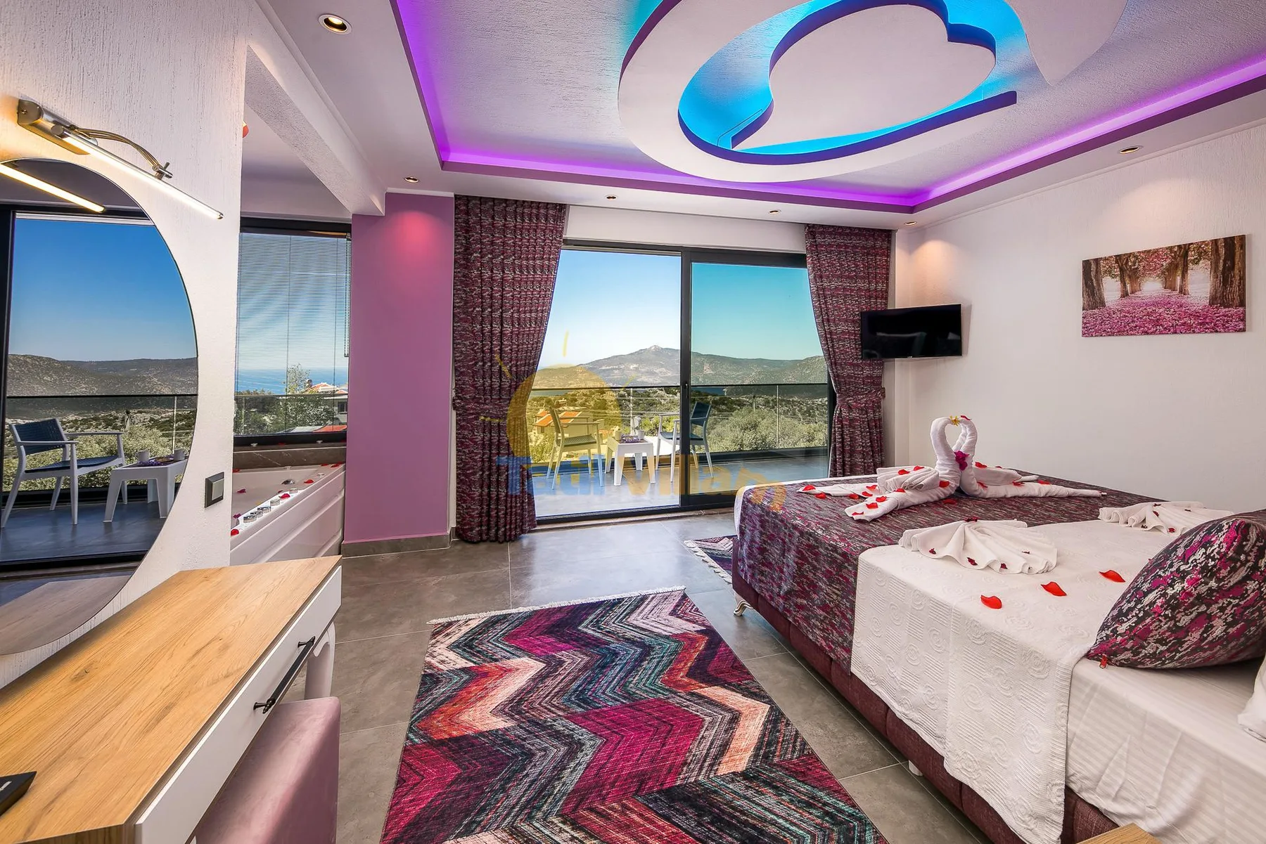 A colorful bedroom with a patterned rug and large windows overlooking the landscape.
