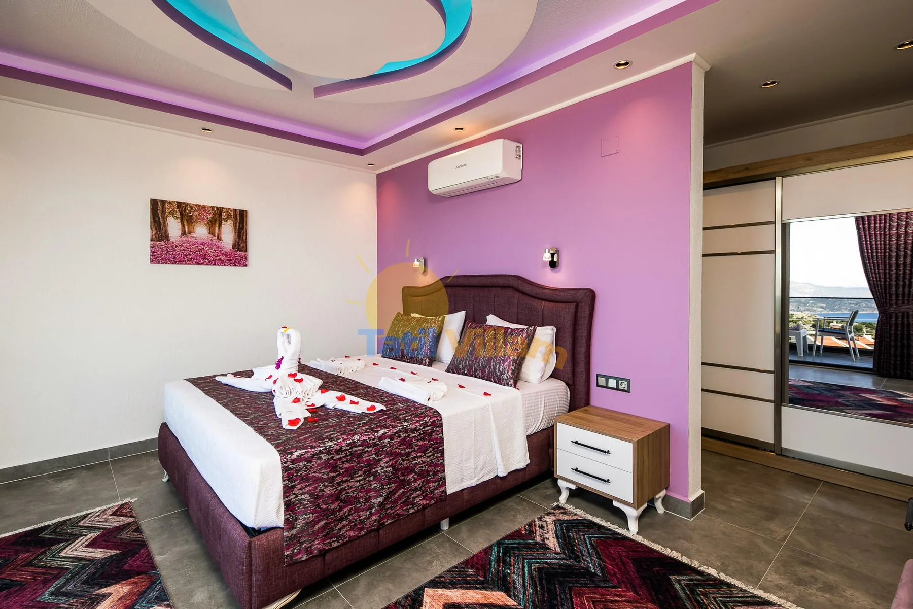A bedroom with a large bed against a pink accent wall.