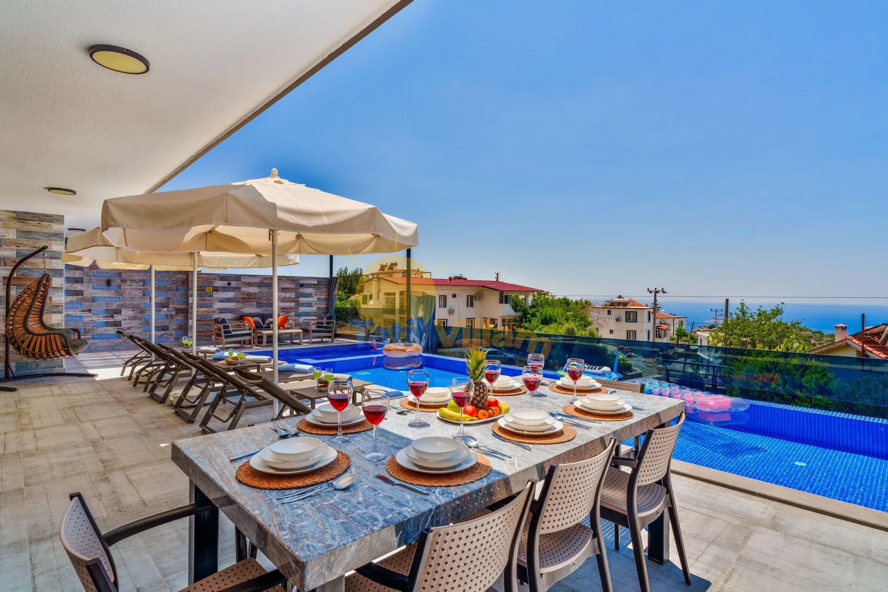 A poolside dining area with a set table and loungers beneath umbrellas.
