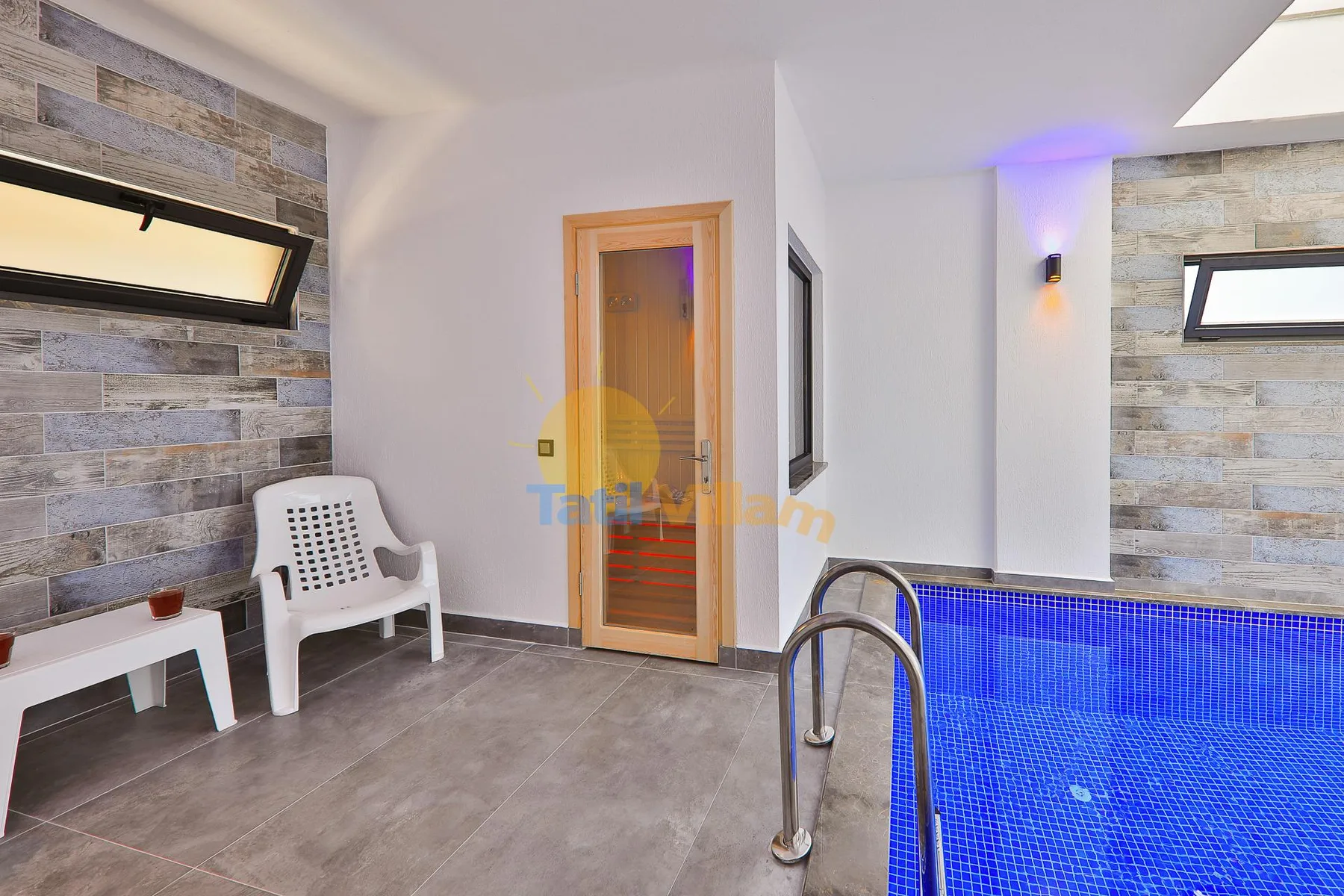 An indoor pool area with blue water, tiled walls, and nearby seating.