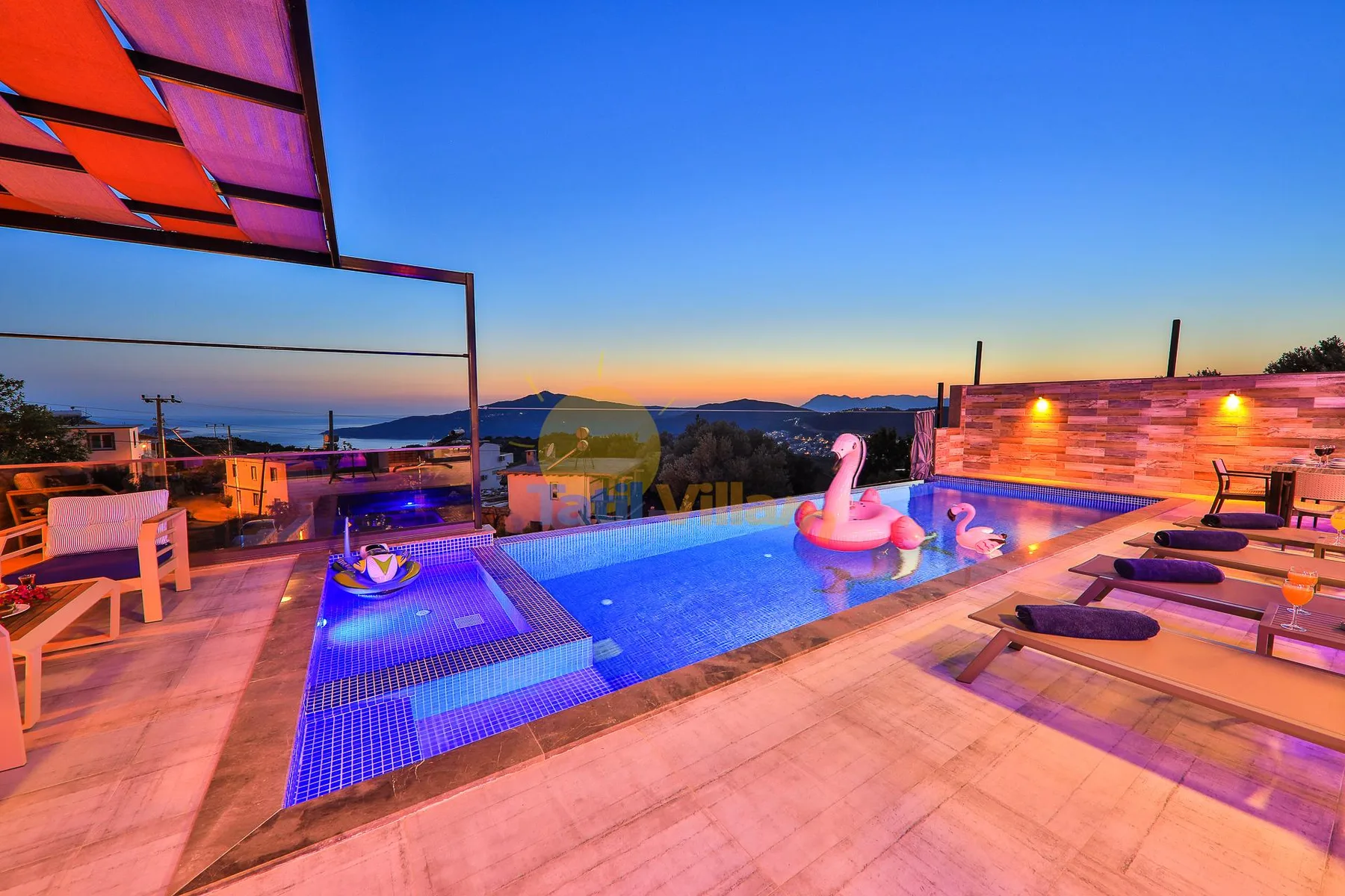 An outdoor pool glows at sunset, with lounge seating and distant hills.
