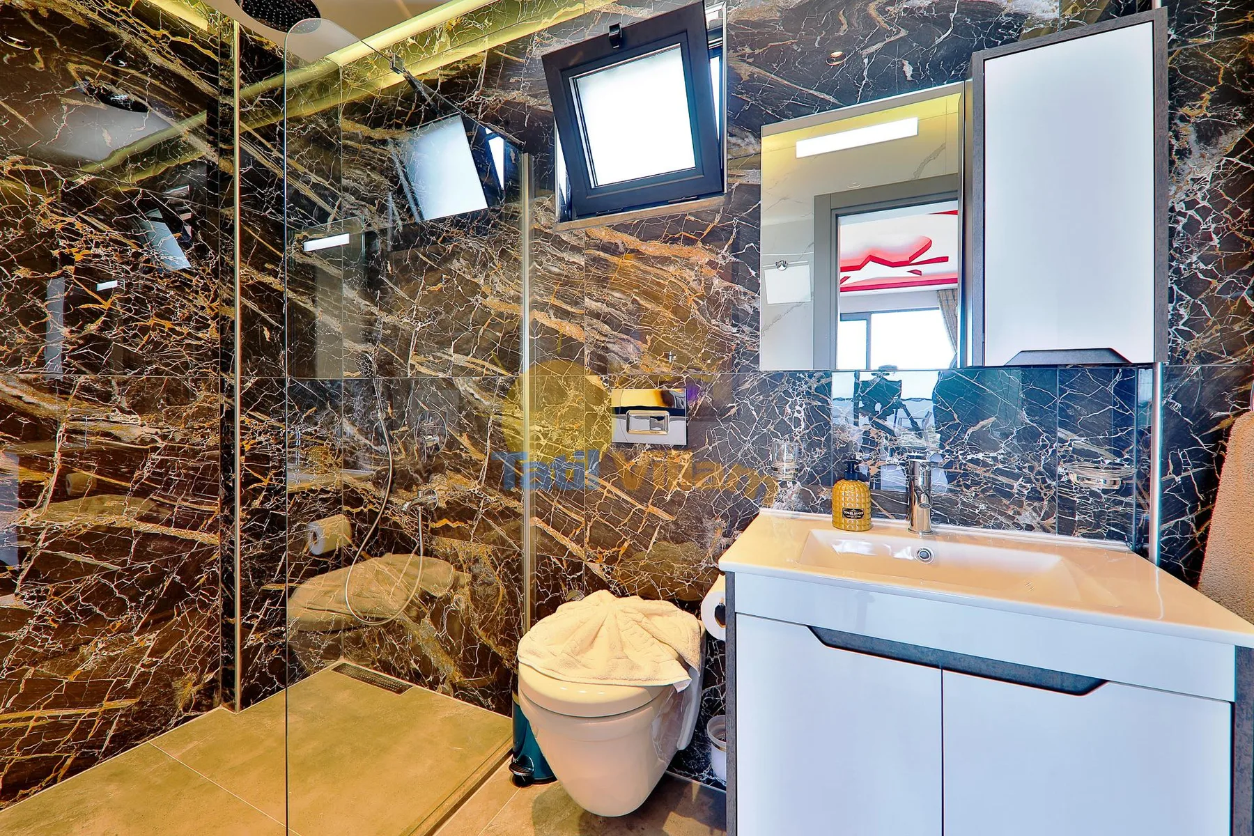 A bathroom with a glass shower, toilet, and white vanity.