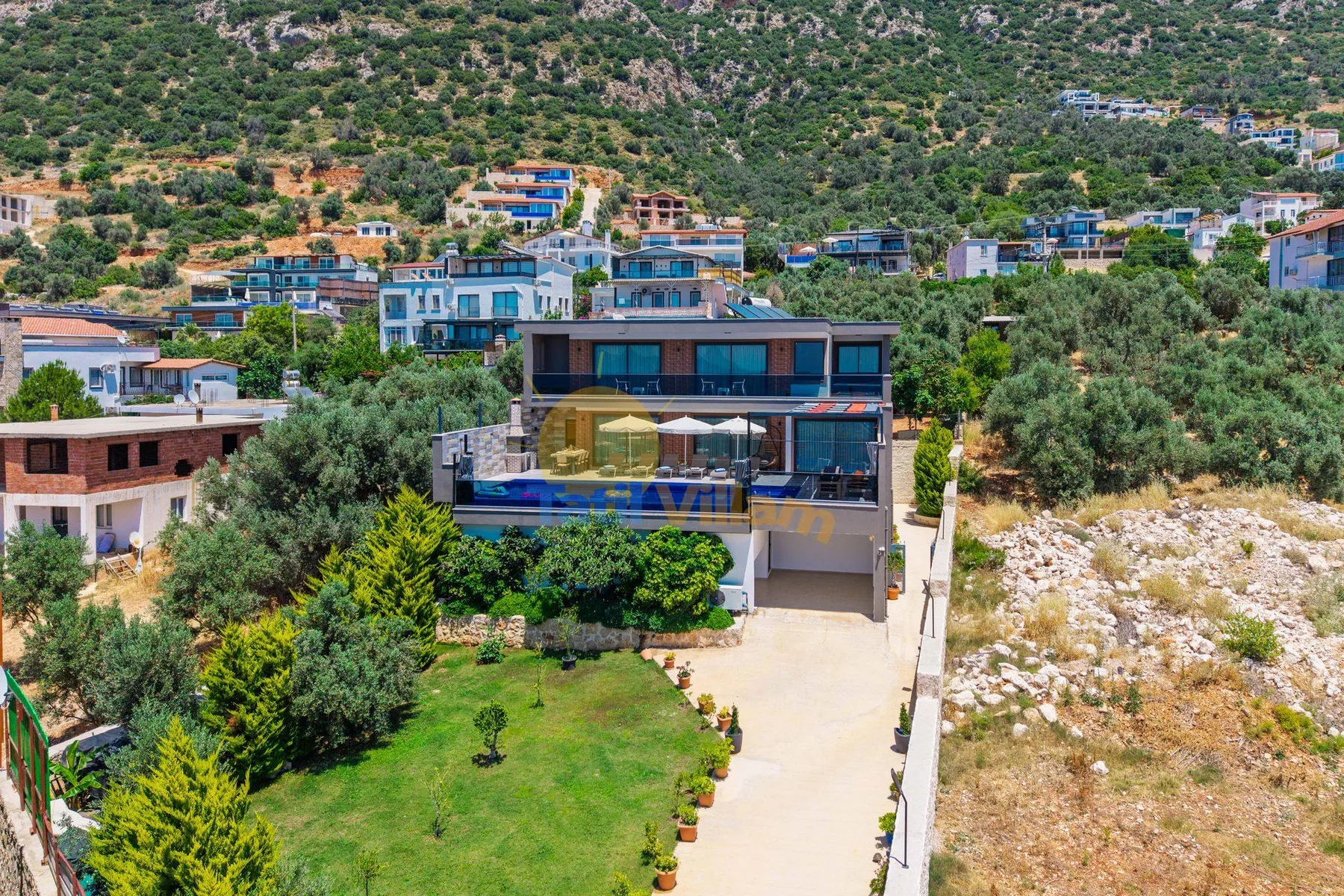 A modern house sits beside a landscaped garden on a hillside.