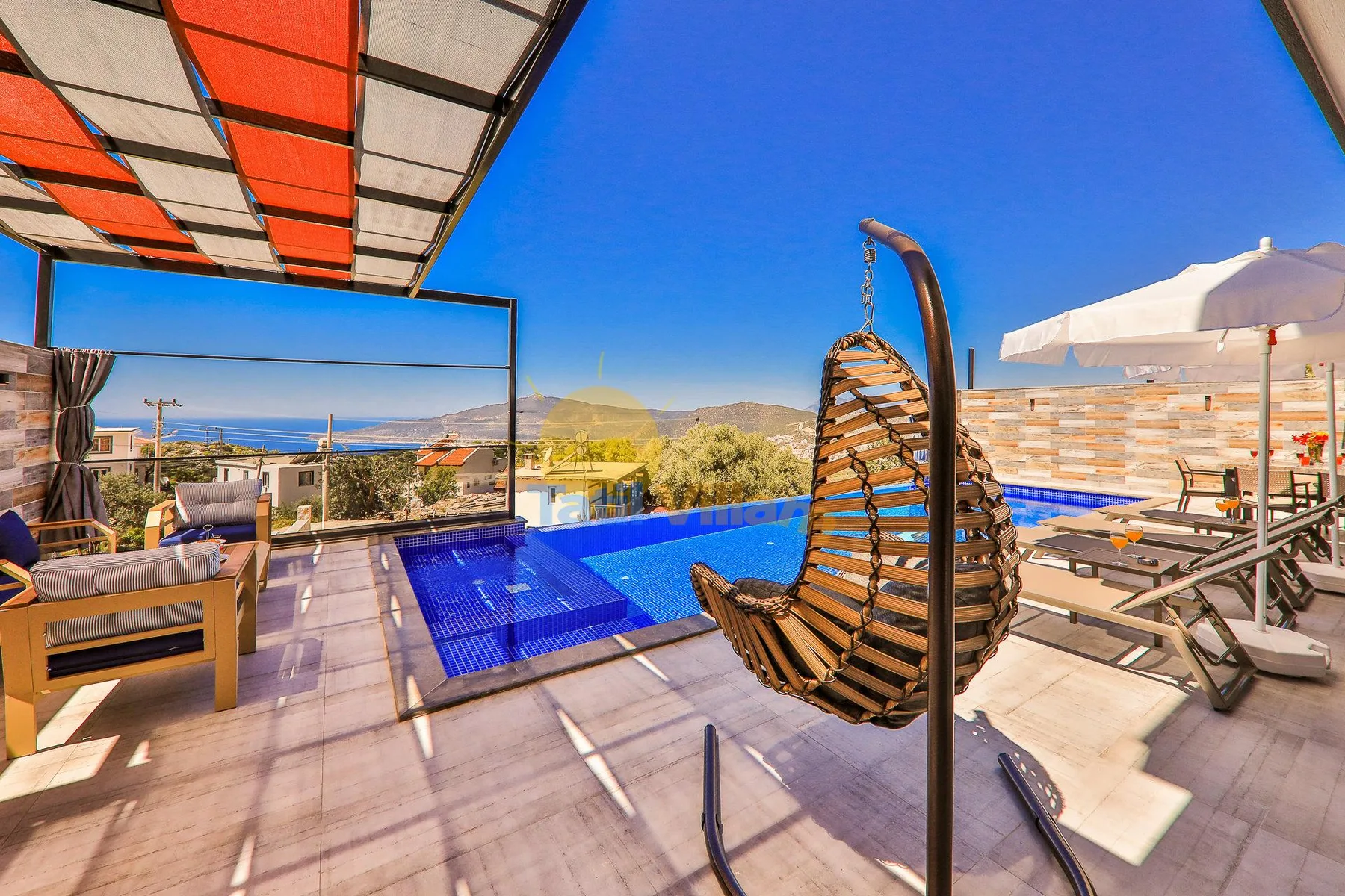 An outdoor pool terrace with a hanging chair and a large sun umbrella.