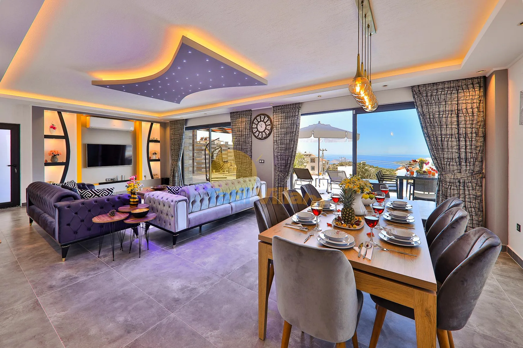 A dining and living area with a set table and seating beside large windows.