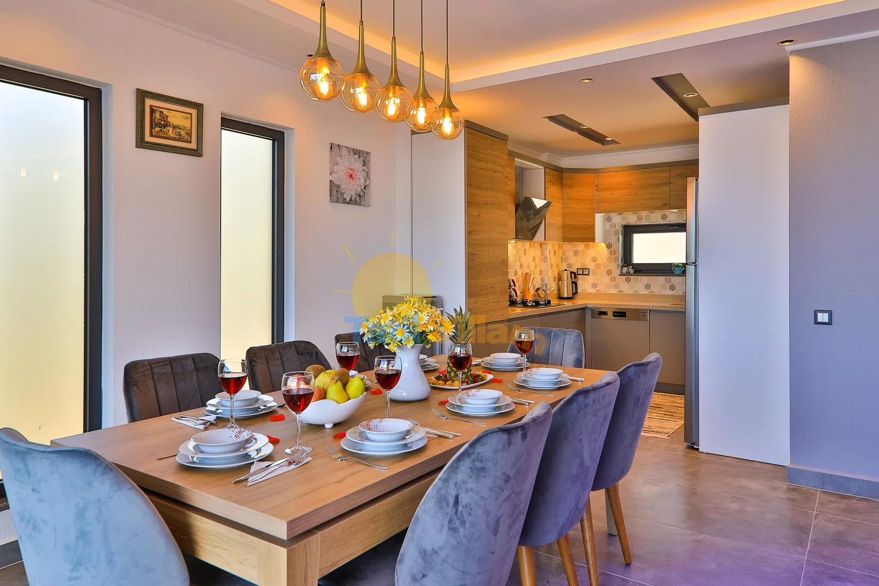 Dining area with a long table set for a meal beside the kitchen.