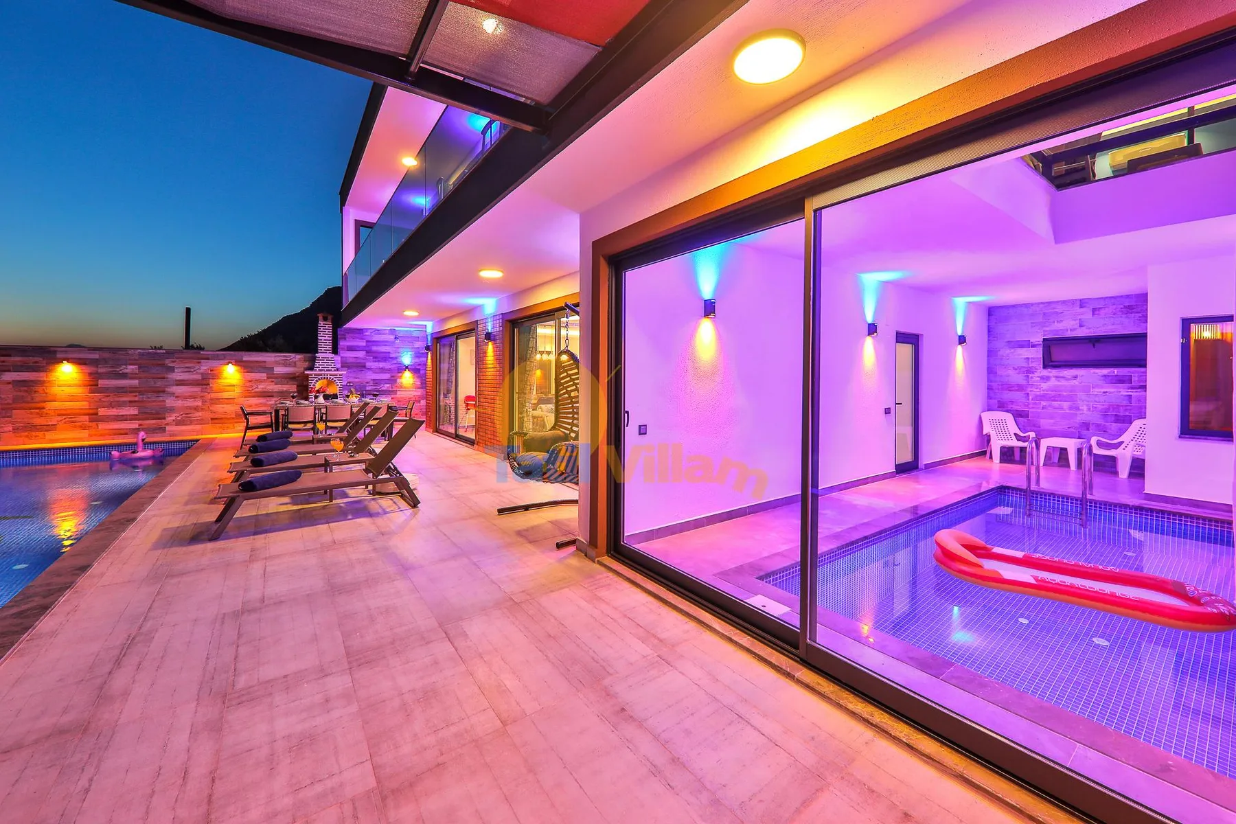 A brightly lit poolside patio with lounge seating beside large glass doors.