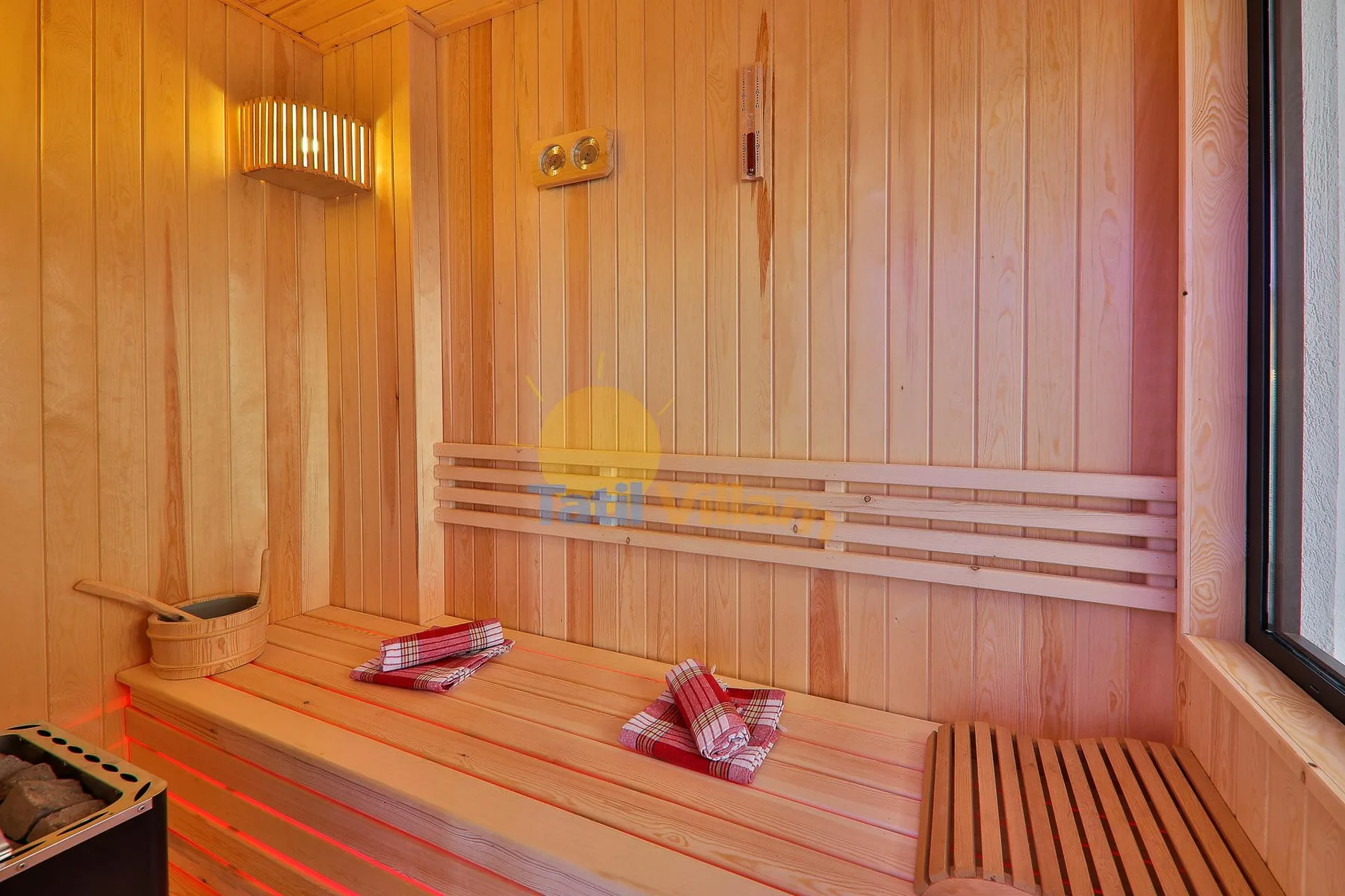 A wood-paneled sauna with tiered seating and a small heater.