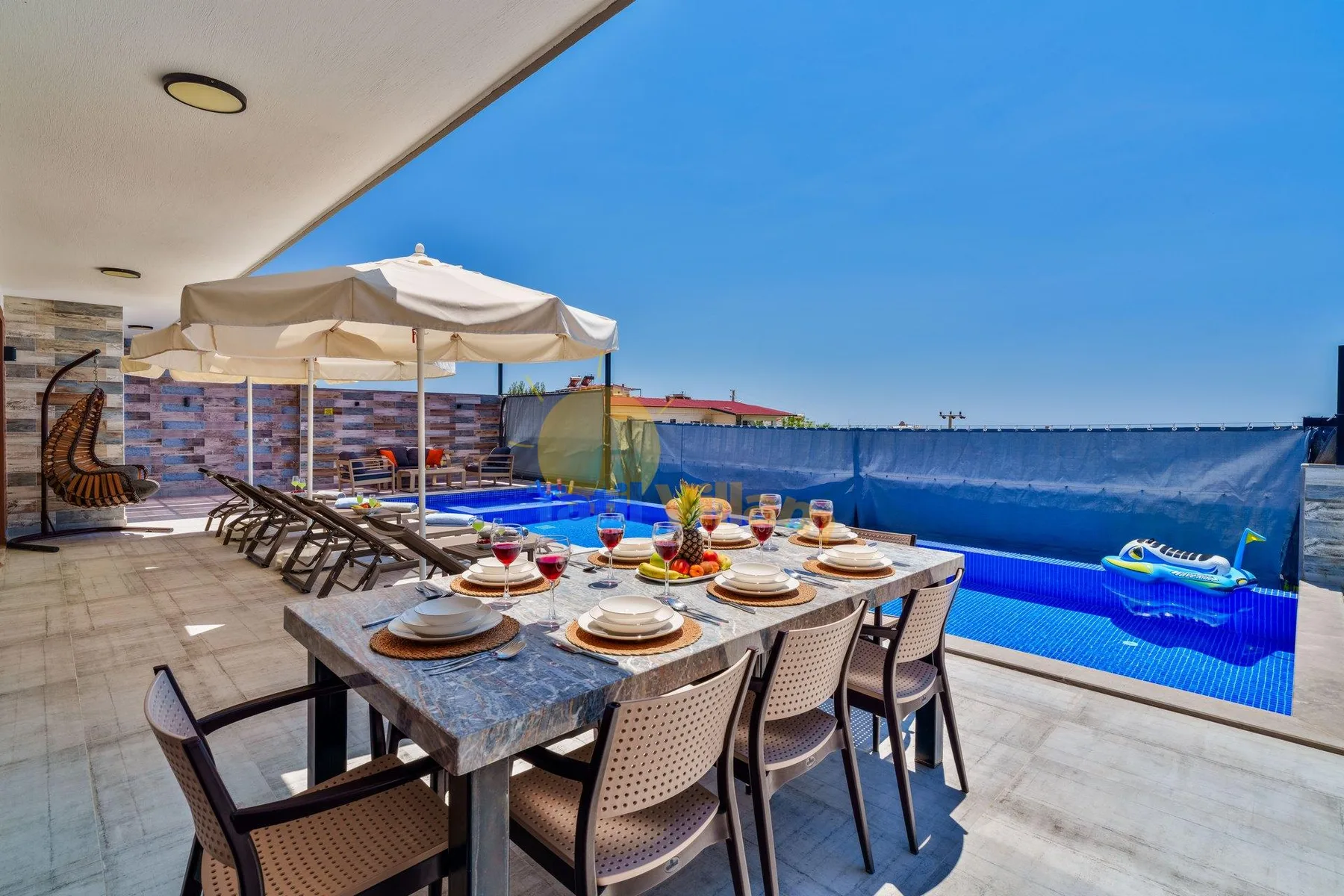 An outdoor dining area beside a swimming pool, with a table set for a meal.