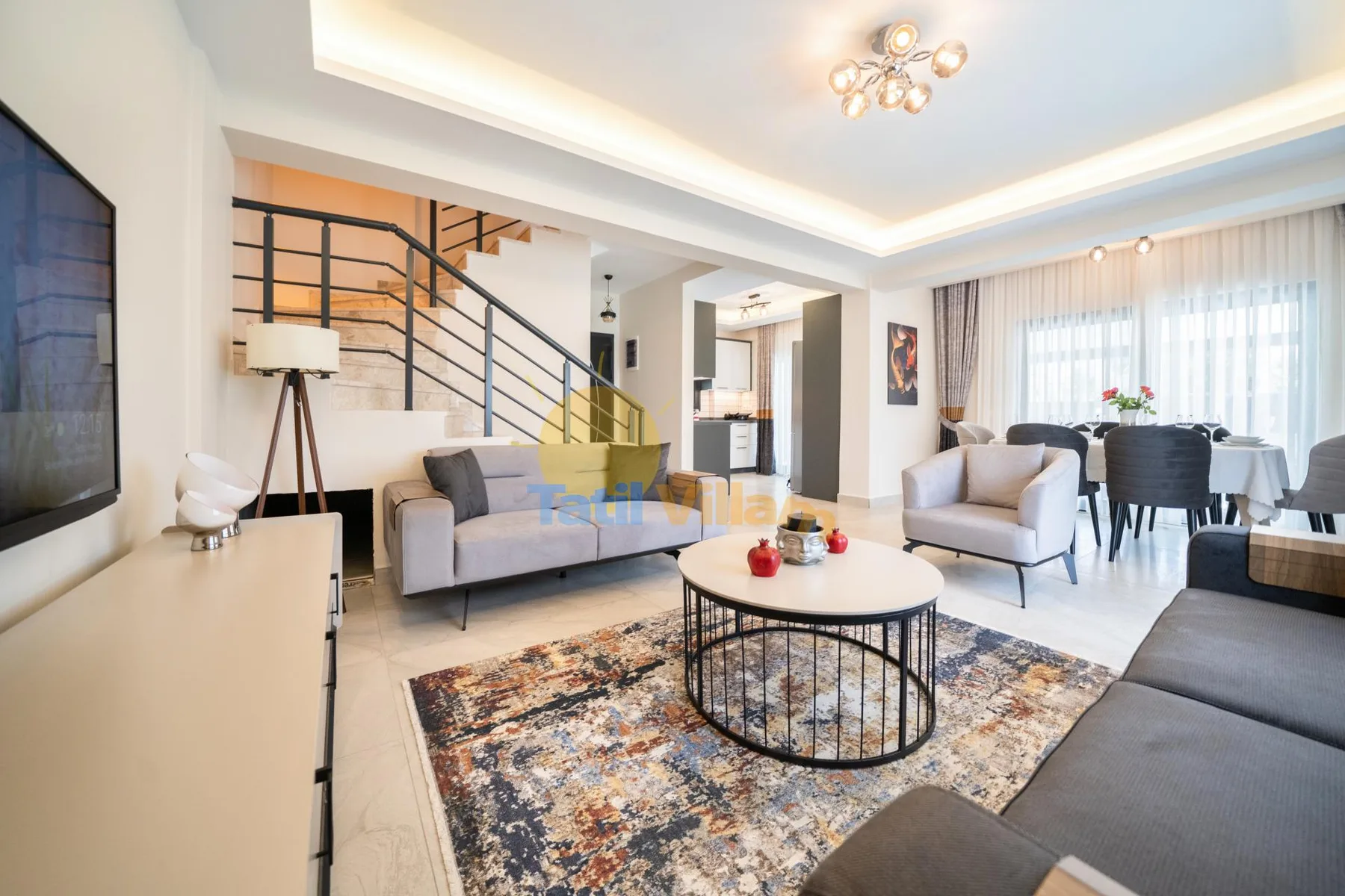 Una sala luminosa con asientos alrededor de una mesa de centro y comedor junto a las ventanas.
