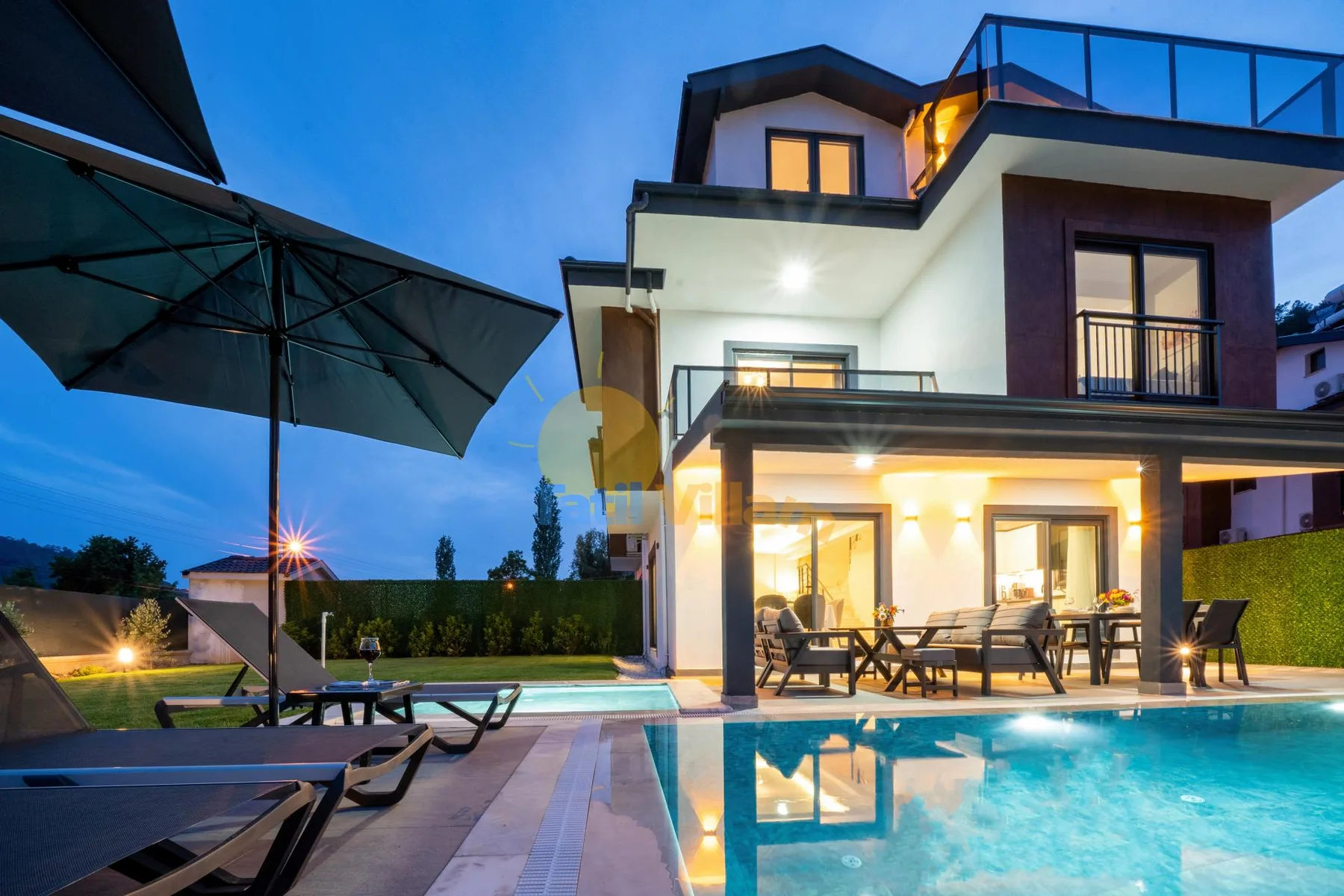 Una casa moderna con un patio iluminado junto a una piscina al anochecer.