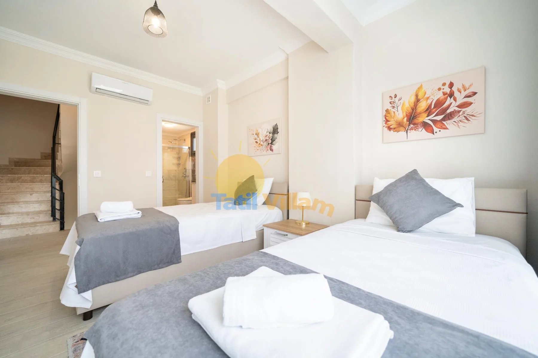 Un dormitorio luminoso con dos camas y un cuadro floral en la pared.