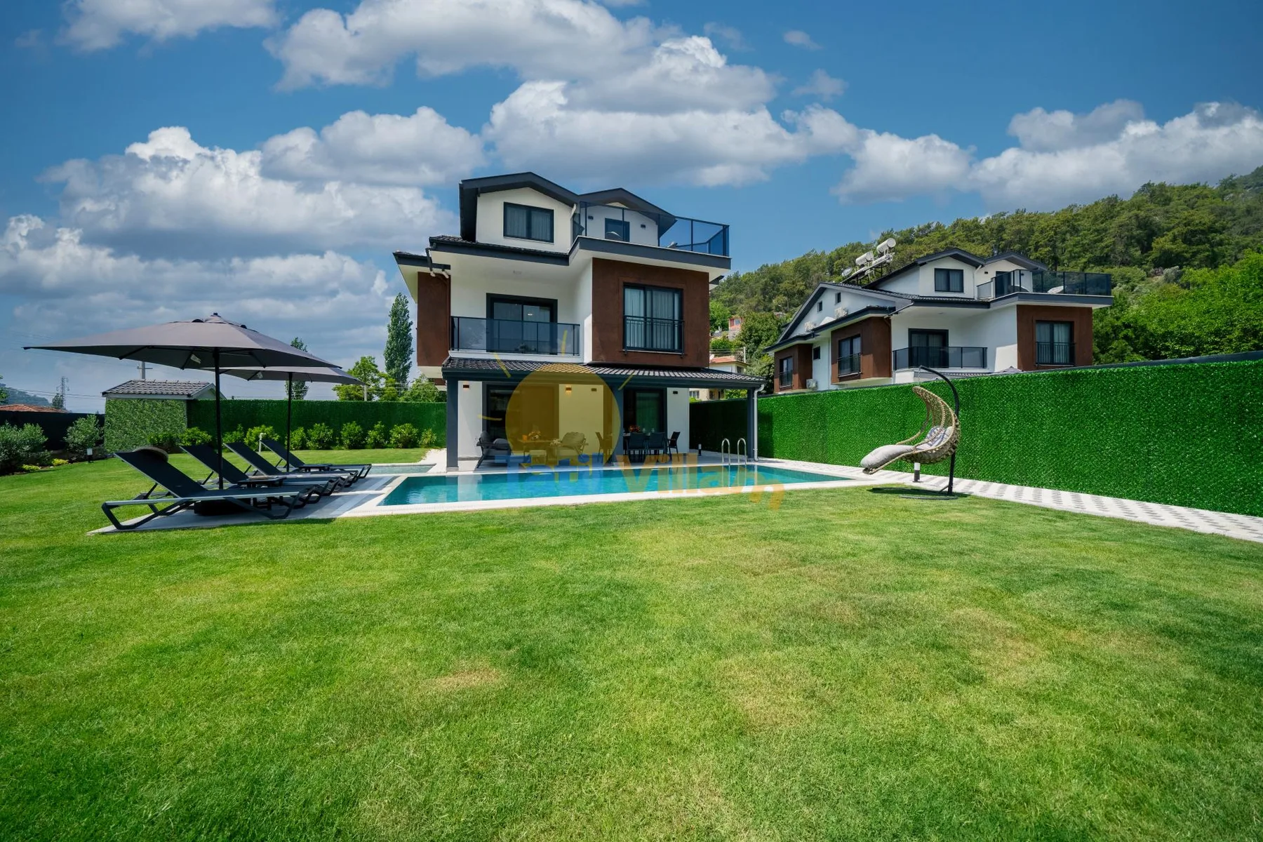 Una casa moderna se encuentra junto a una piscina y un amplio césped verde.